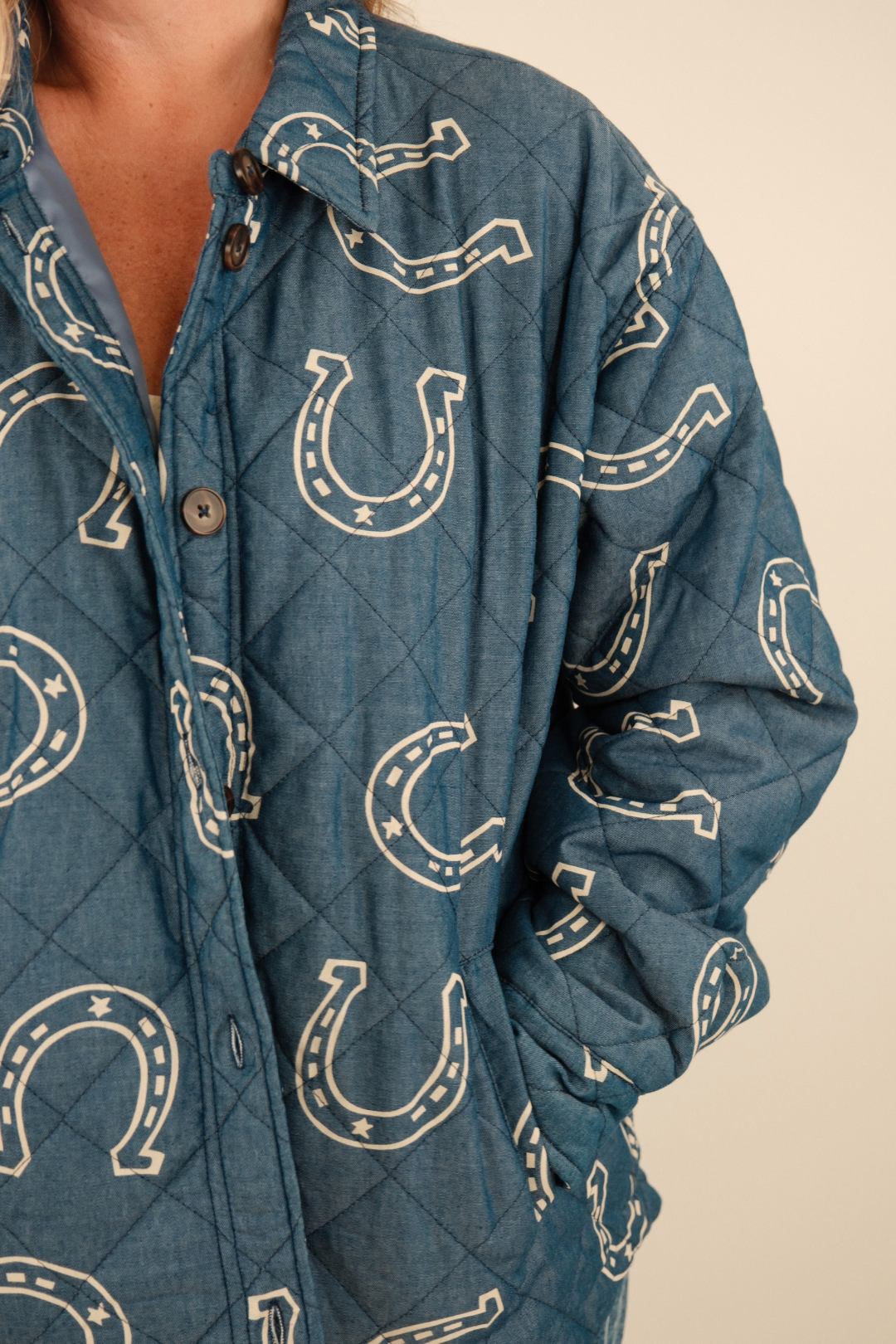 Side profile of Lucky Stitch Quilted Denim Jacket showing quilted medium wash denim, cream horseshoe pattern, and front pocket detail.