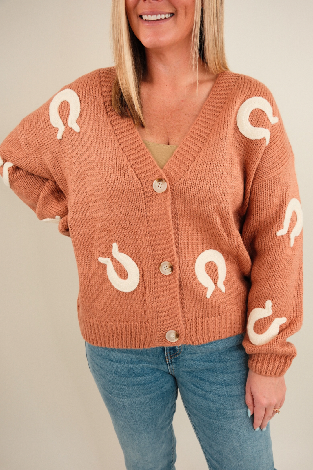 Close-up of Lucky Stitches Cardigan highlighting textured knit fabric, cream horseshoe embroidery and button detail.