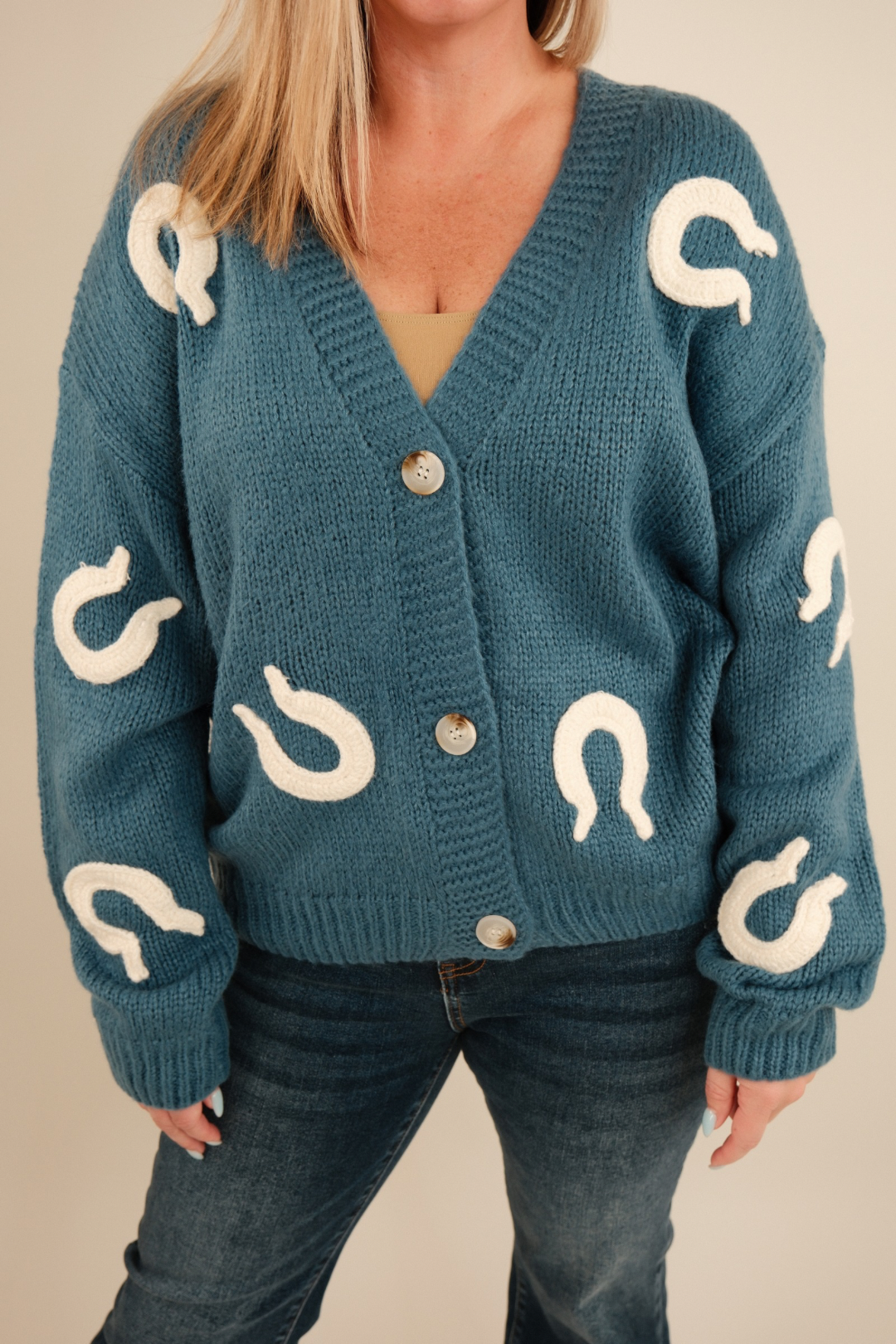 Close-up of Lucky Stitches Cardigan highlighting textured knit fabric, cream horseshoe embroidery and button detail.