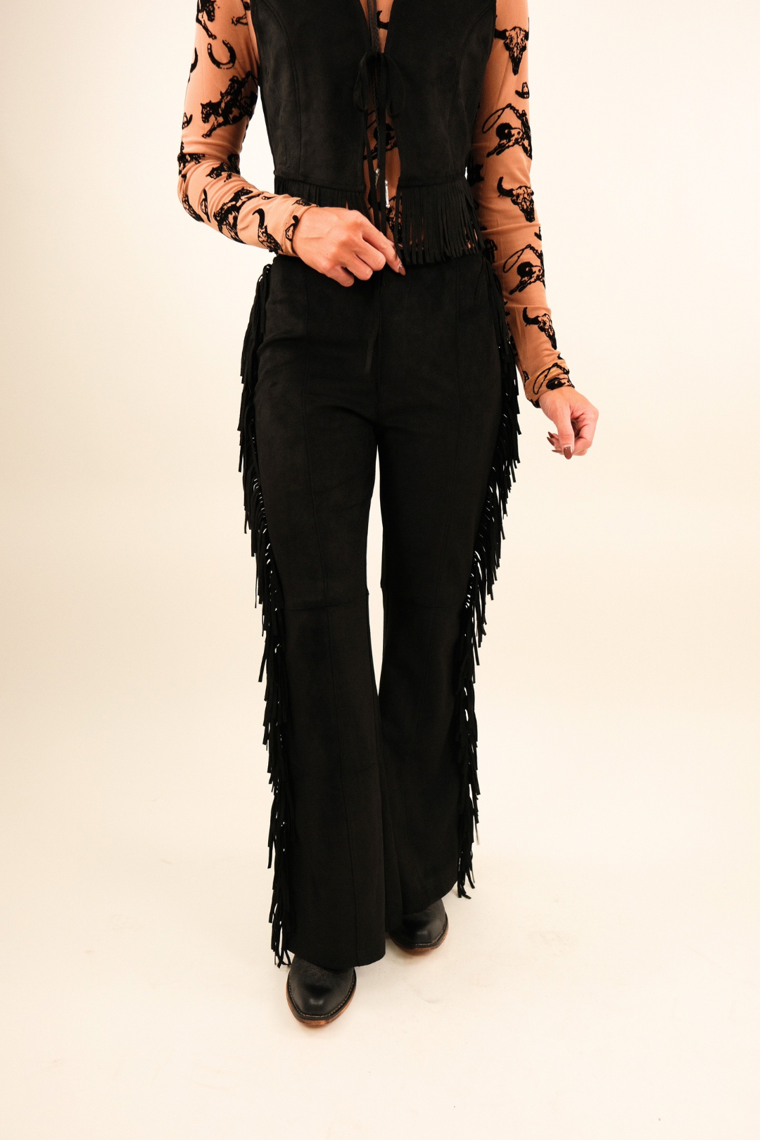 Front view of Midnight Fringe Suede Pants, luxe black suede high-rise pants with sleek fit and bold western fringe along each leg.