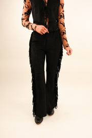 Front view of Midnight Fringe Suede Pants, luxe black suede high-rise pants with sleek fit and bold western fringe along each leg.