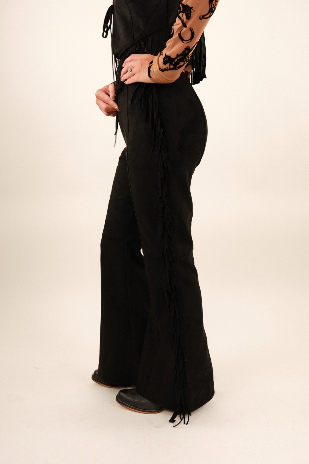 Side profile of Midnight Fringe Suede Pants in black suede showing cascading fringe down the leg and flattering high-rise fit.