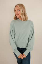 Sky blue waist-length fleece with mock neck and soft brushed texture, relaxed pullover style.