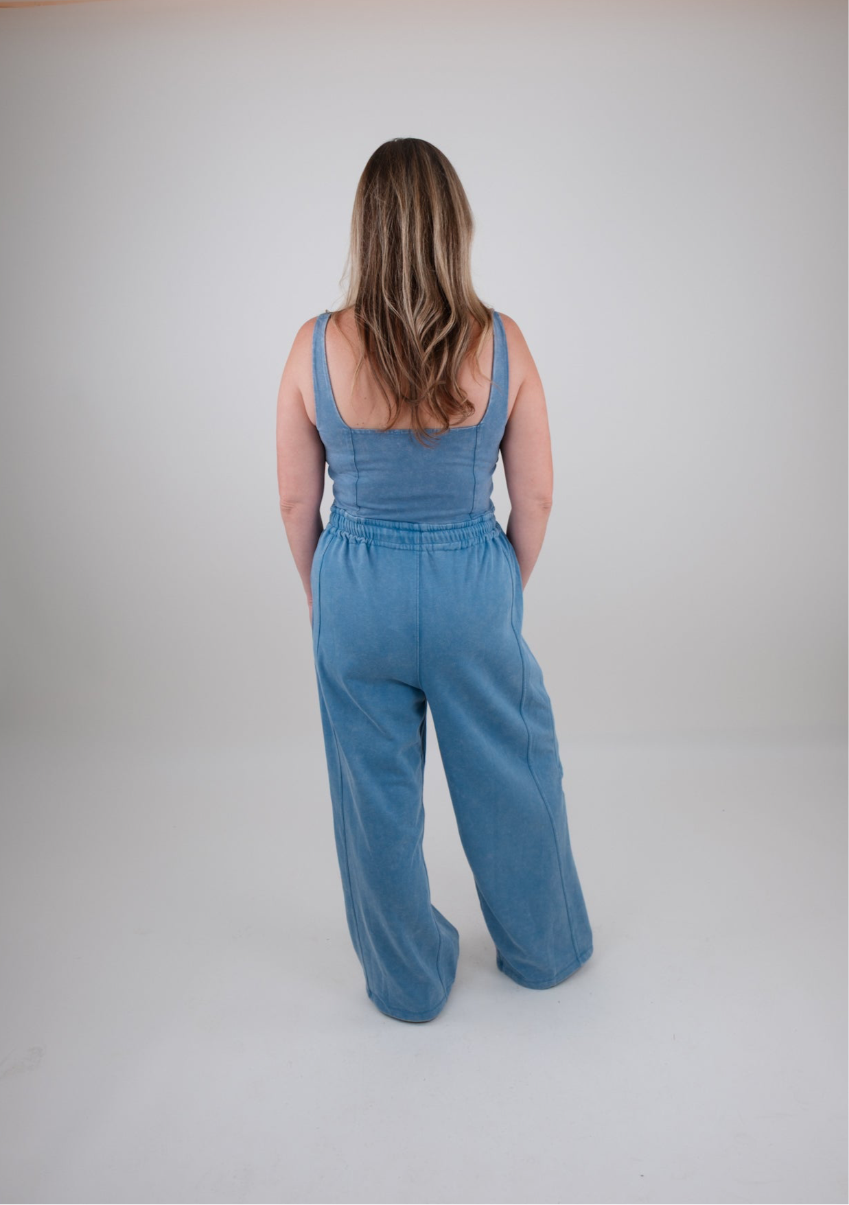 Woman wearing a blue jumpsuit on a plain background