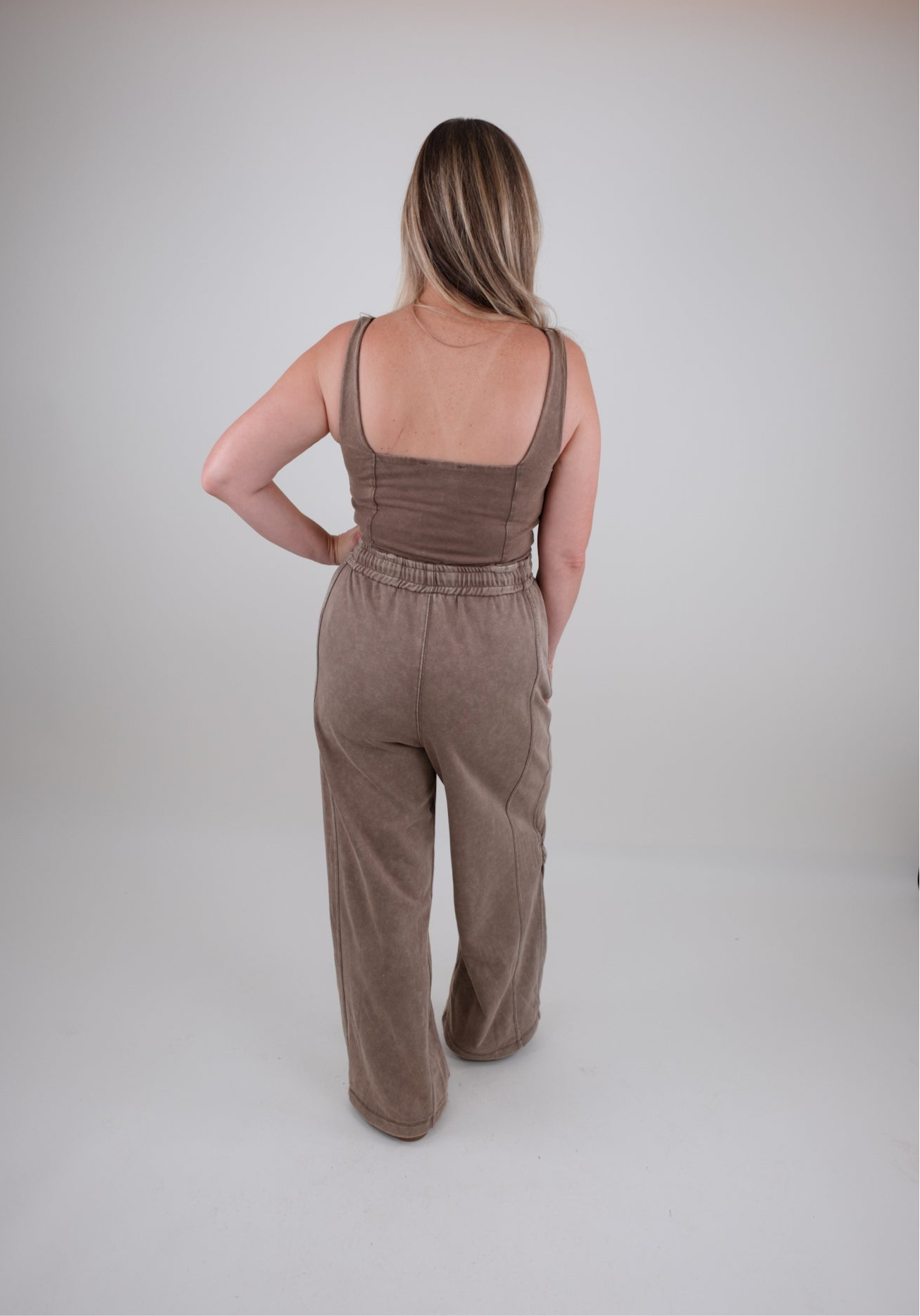 Person wearing a brown jumpsuit on a plain background