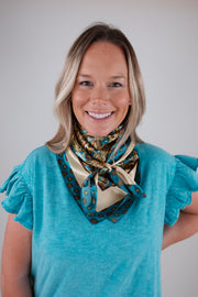Woman wearing a blue top and patterned scarf against a plain background