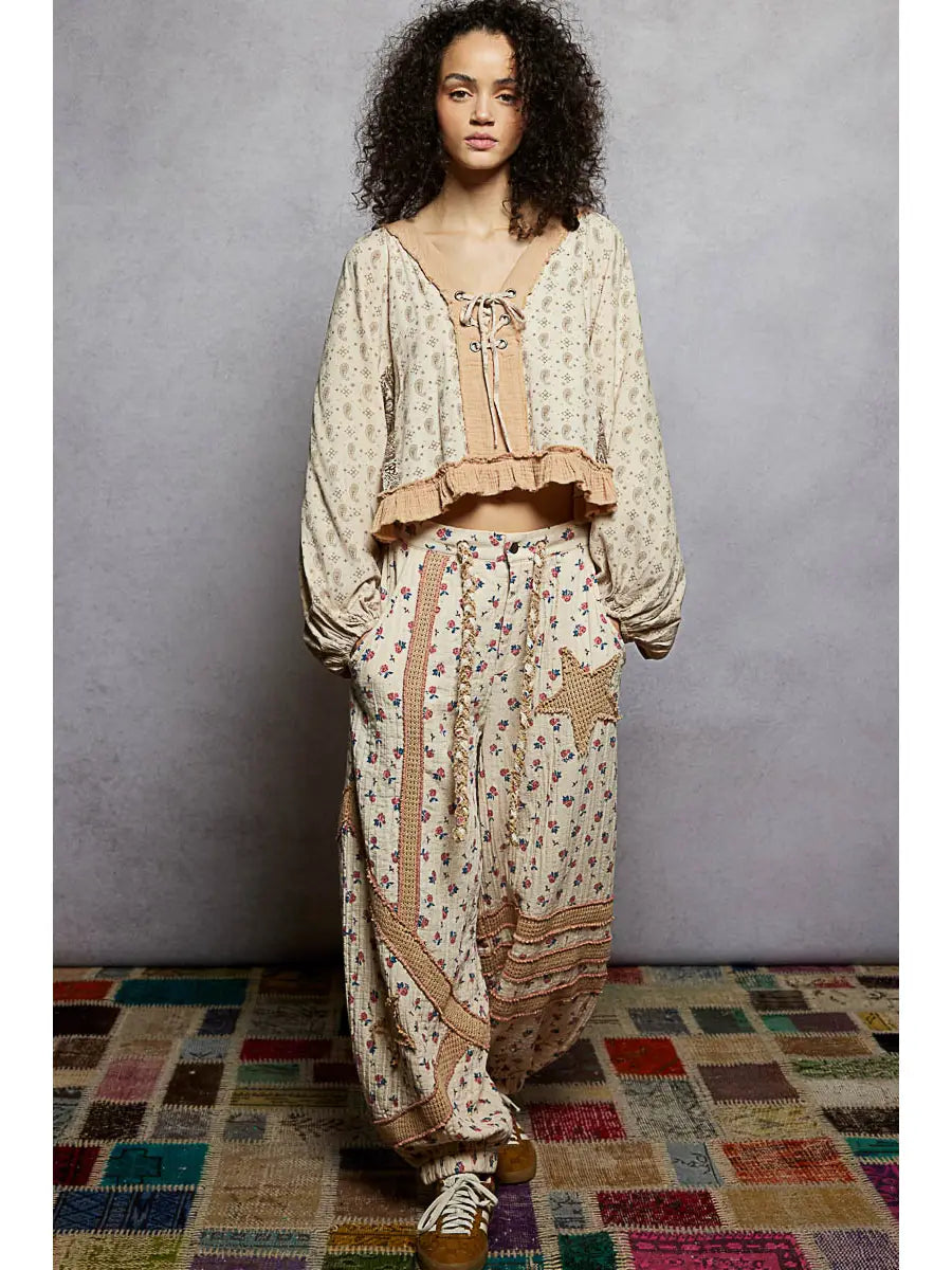 Woman wearing a patterned outfit standing on a colorful rug with a gray wall background