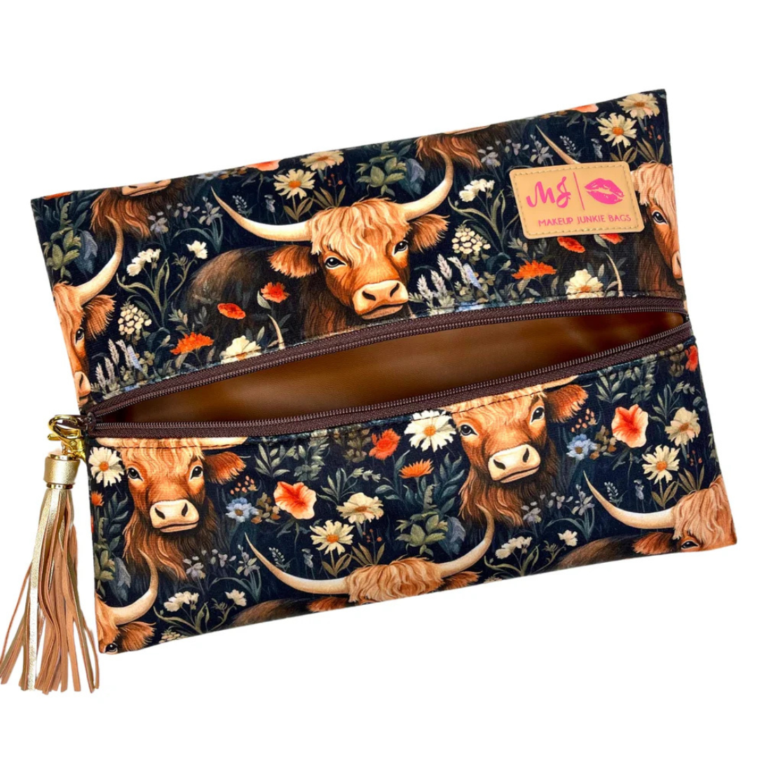 Front view of Prairie travel bag with black floral‑western Highland cow print on velvet, black zipper and gold tassel accent.
