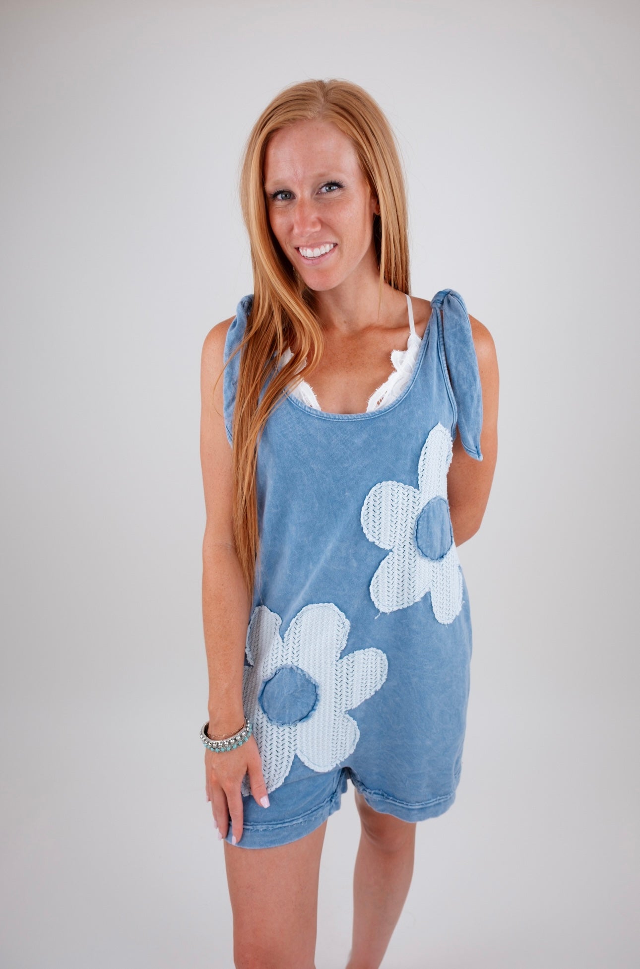 Woman wearing a blue romper with white floral patterns on a plain background