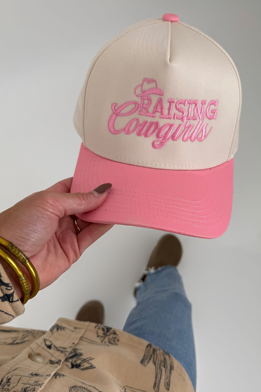 Beige and light pink cowboy hat with embroidered ‘Raising Cowgirls’ slogan and classic western brim