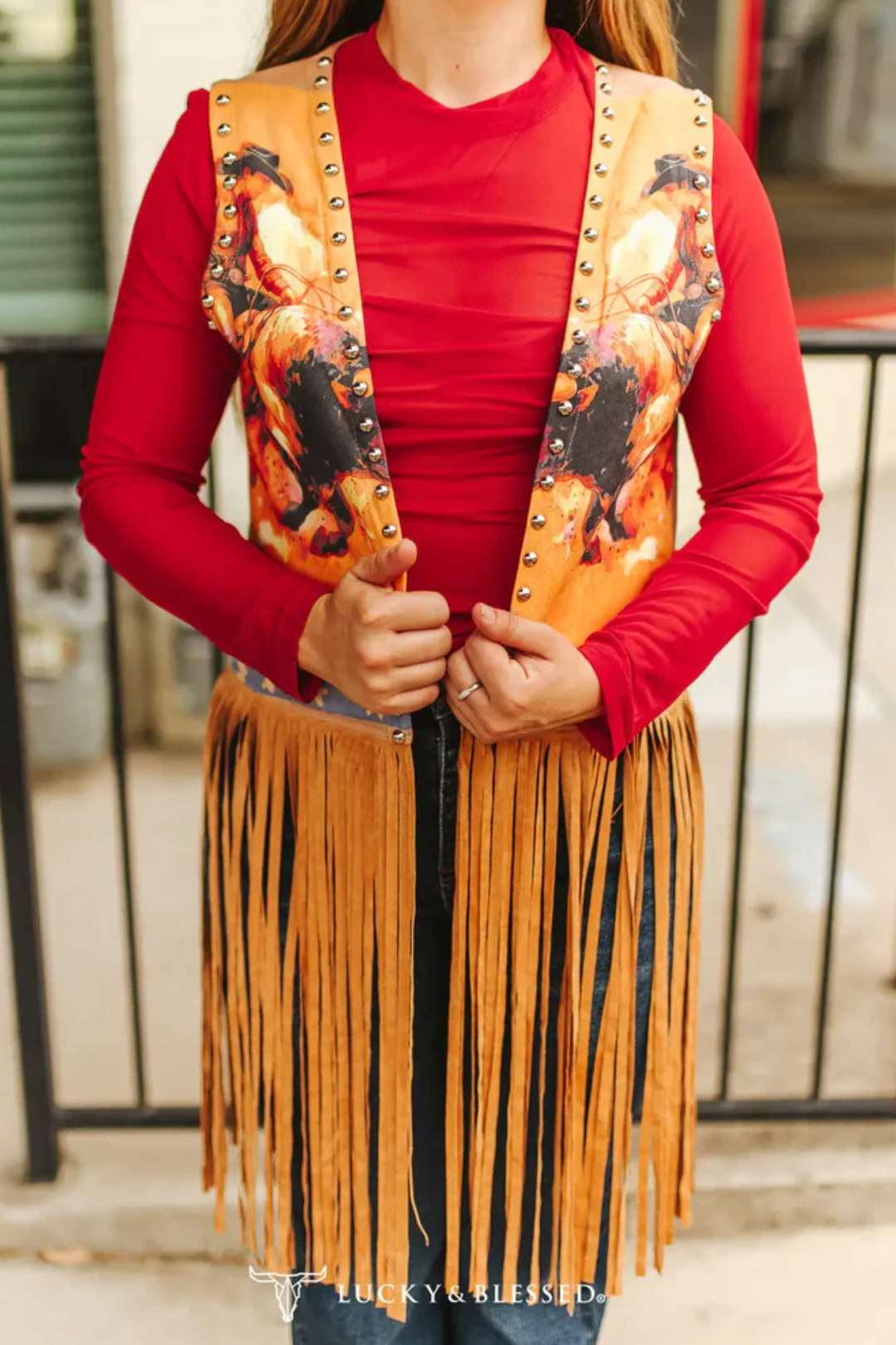 Person wearing a red shirt and a decorative vest with fringes and patterns.