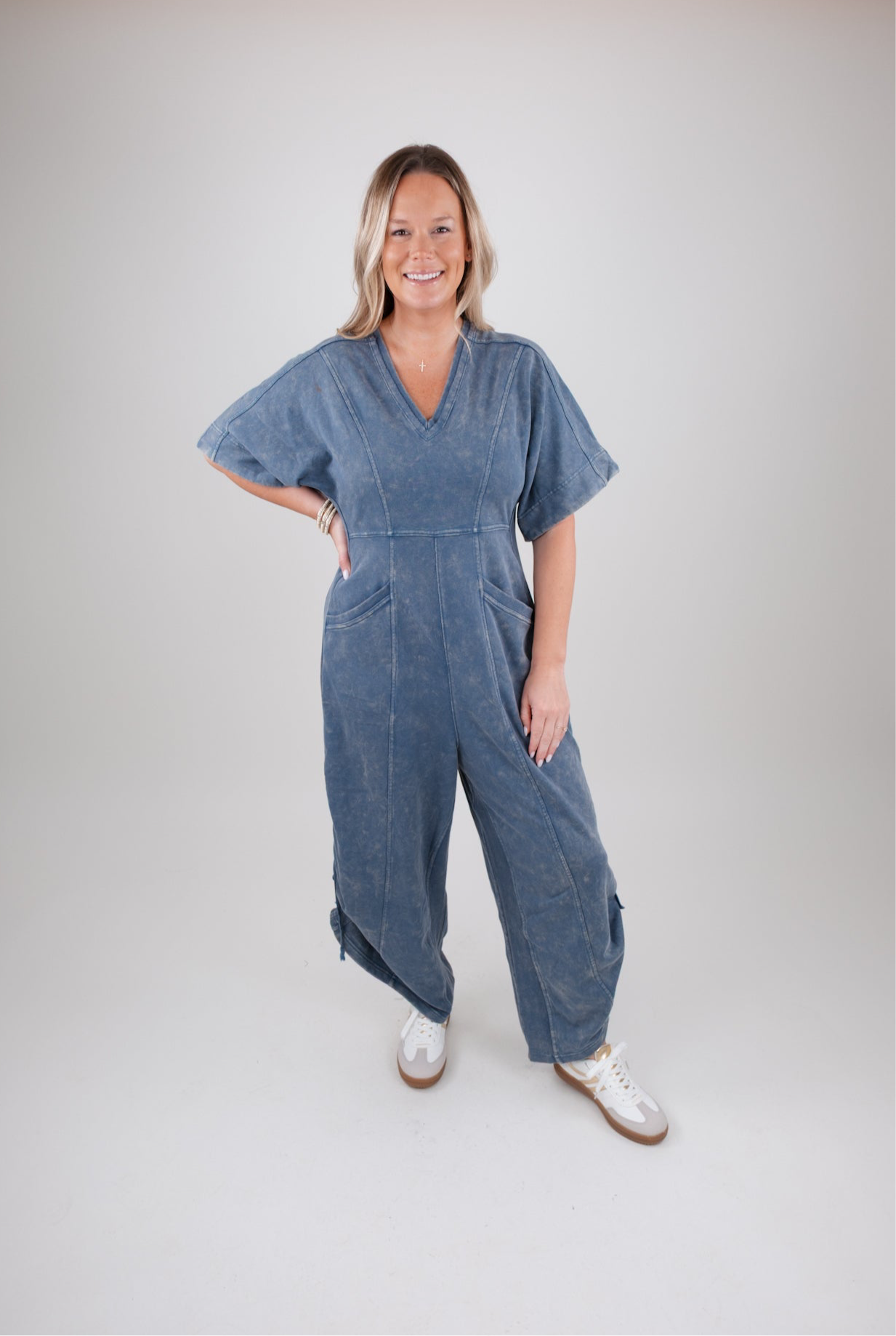 Woman wearing a blue denim jumpsuit on a plain background