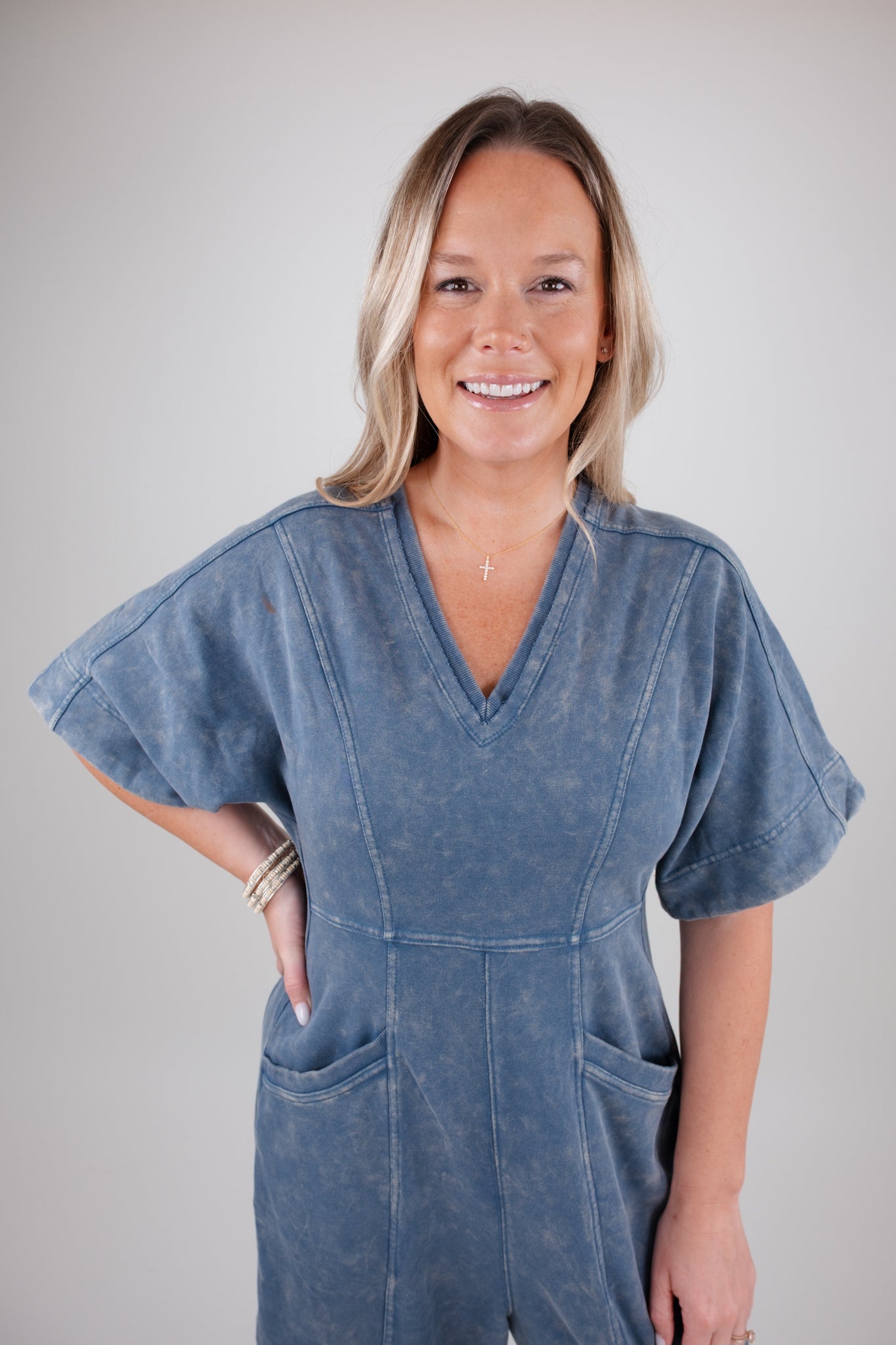 Woman wearing a blue denim jumpsuit against a plain background