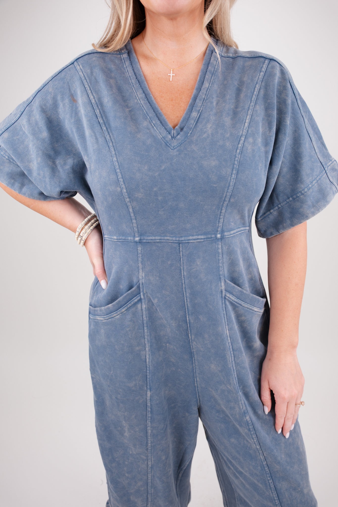 Person wearing a blue denim jumpsuit against a plain background