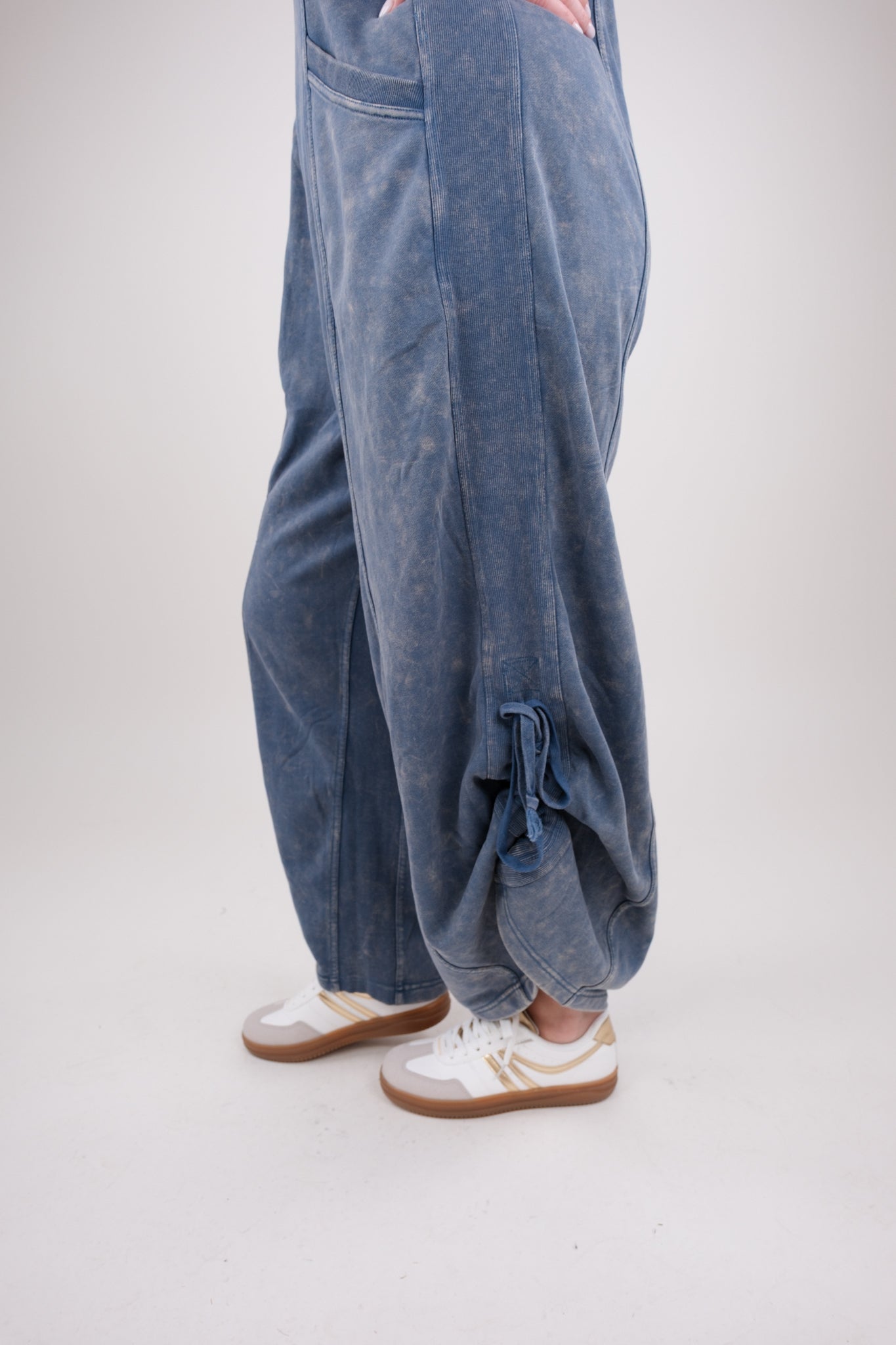 Blue ruched pants worn by a person on a white background