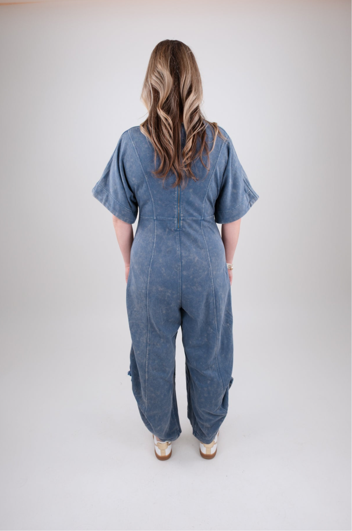 Person wearing a blue denim jumpsuit on a plain background
