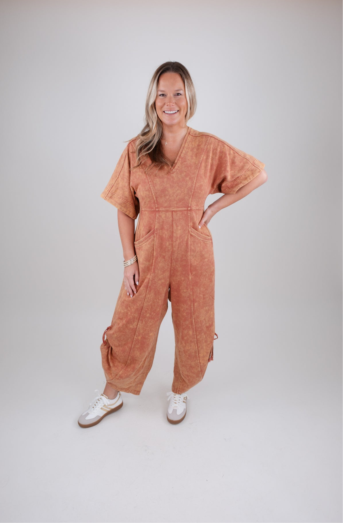 Woman wearing a rust colored jumpsuit on a white background