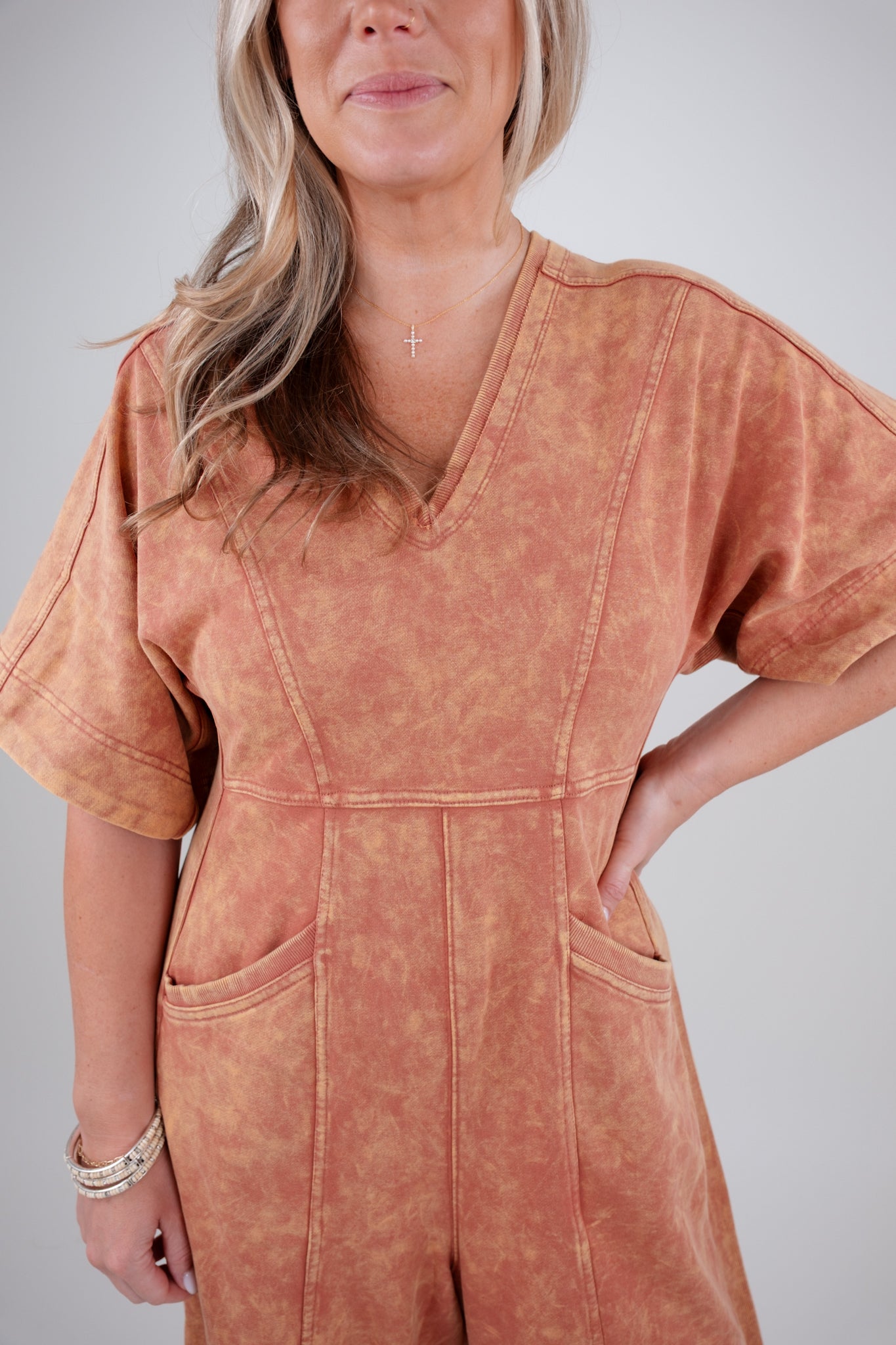 Person wearing a rust colored jumpsuit against a plain background