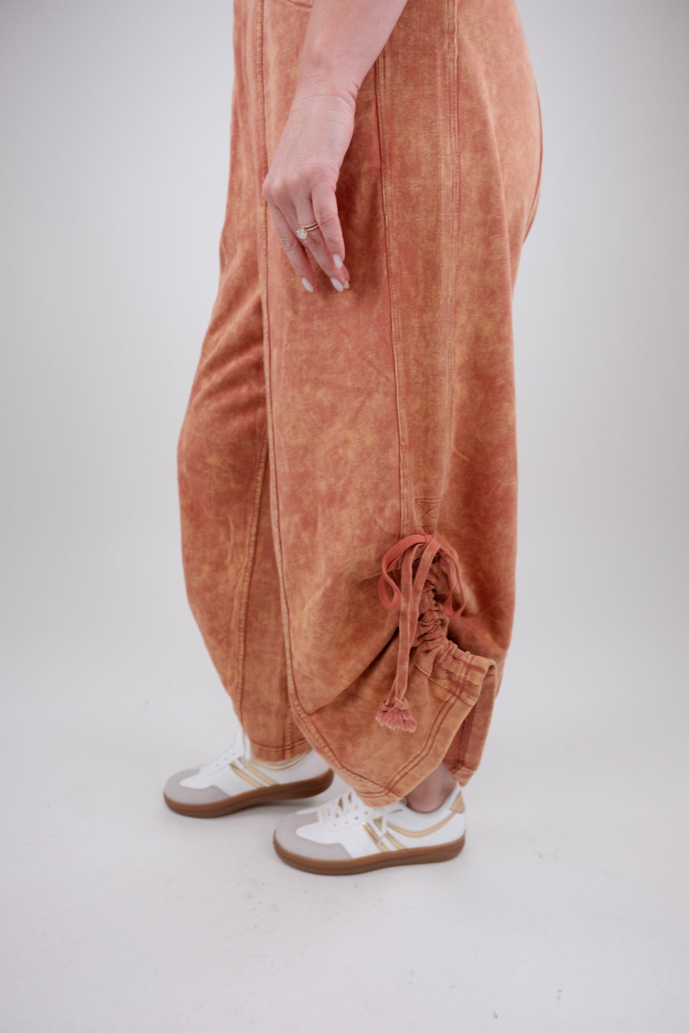 Person wearing rust colored pants with a white background