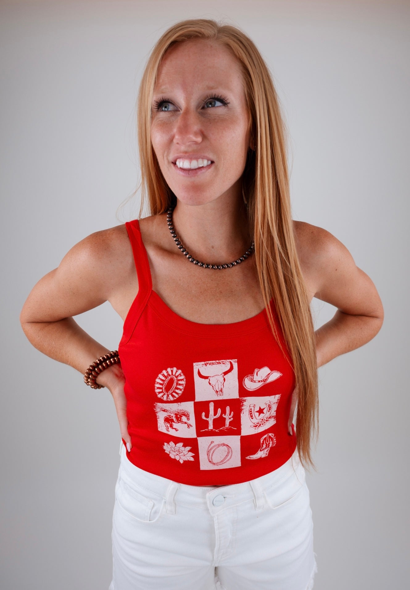 Woman wearing a red tank top with white patterns on a plain background