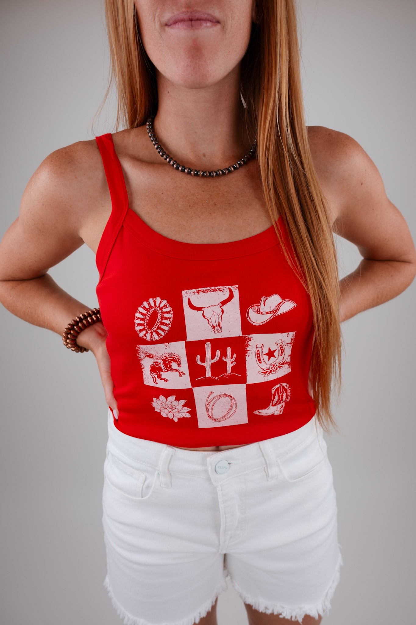 Person wearing a red tank top with white graphic designs on a plain background