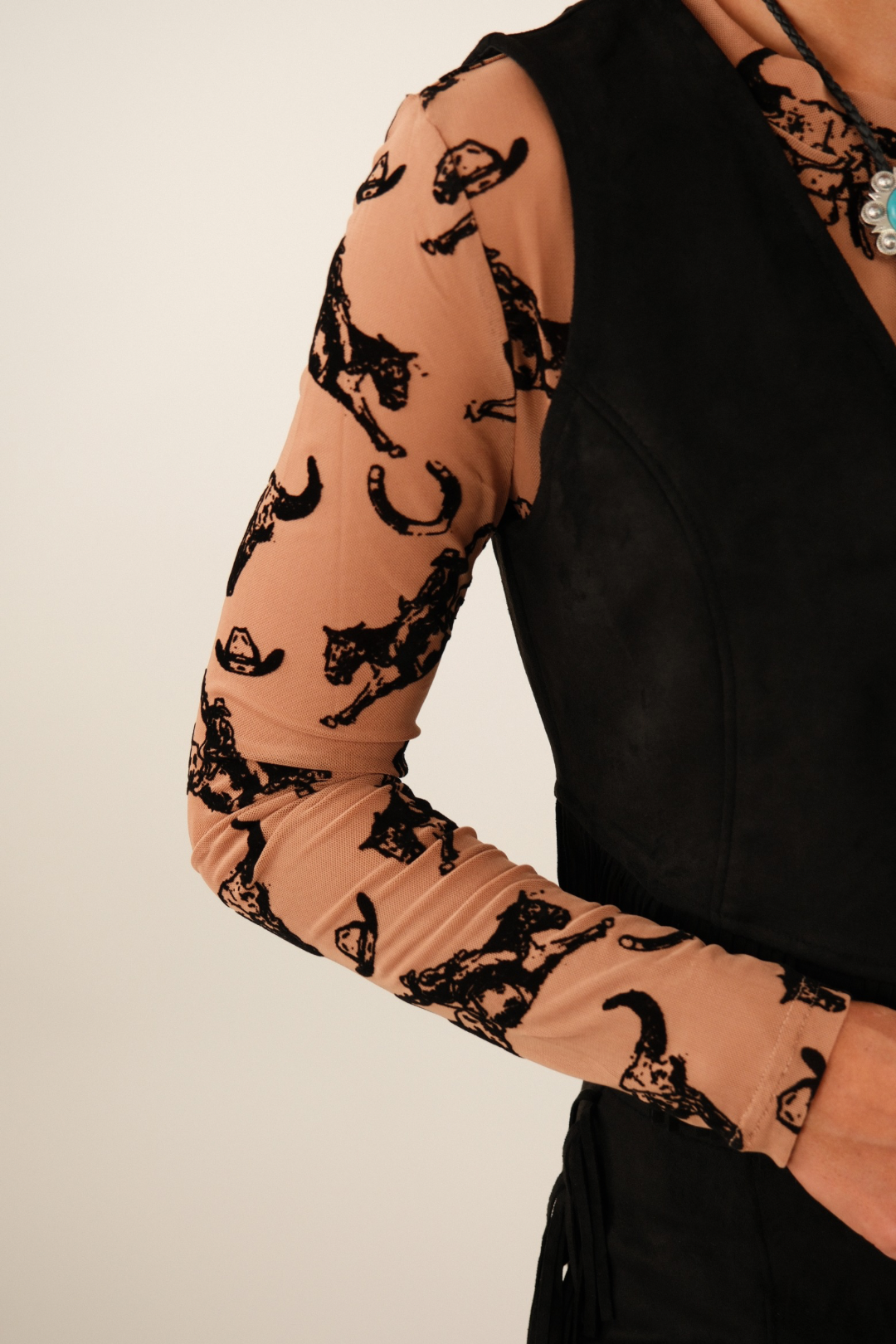 Close-up of Rodeo Relic mesh top showing black velvet 3D cowboy and skull motifs on sheer brown fabric.