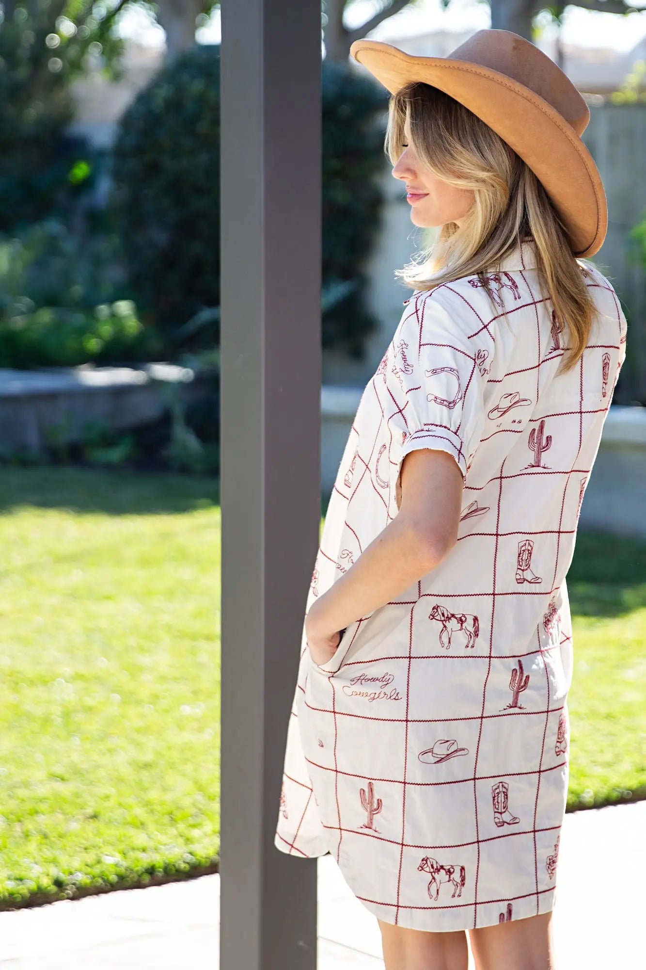 Woman wearing a patterned dress and hat in an outdoor setting