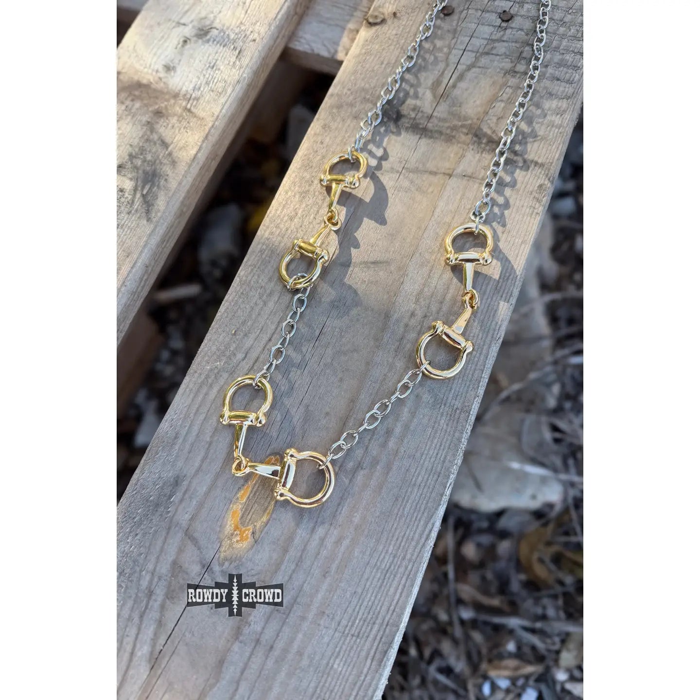 Gold and silver bit chain necklace on a wooden surface.