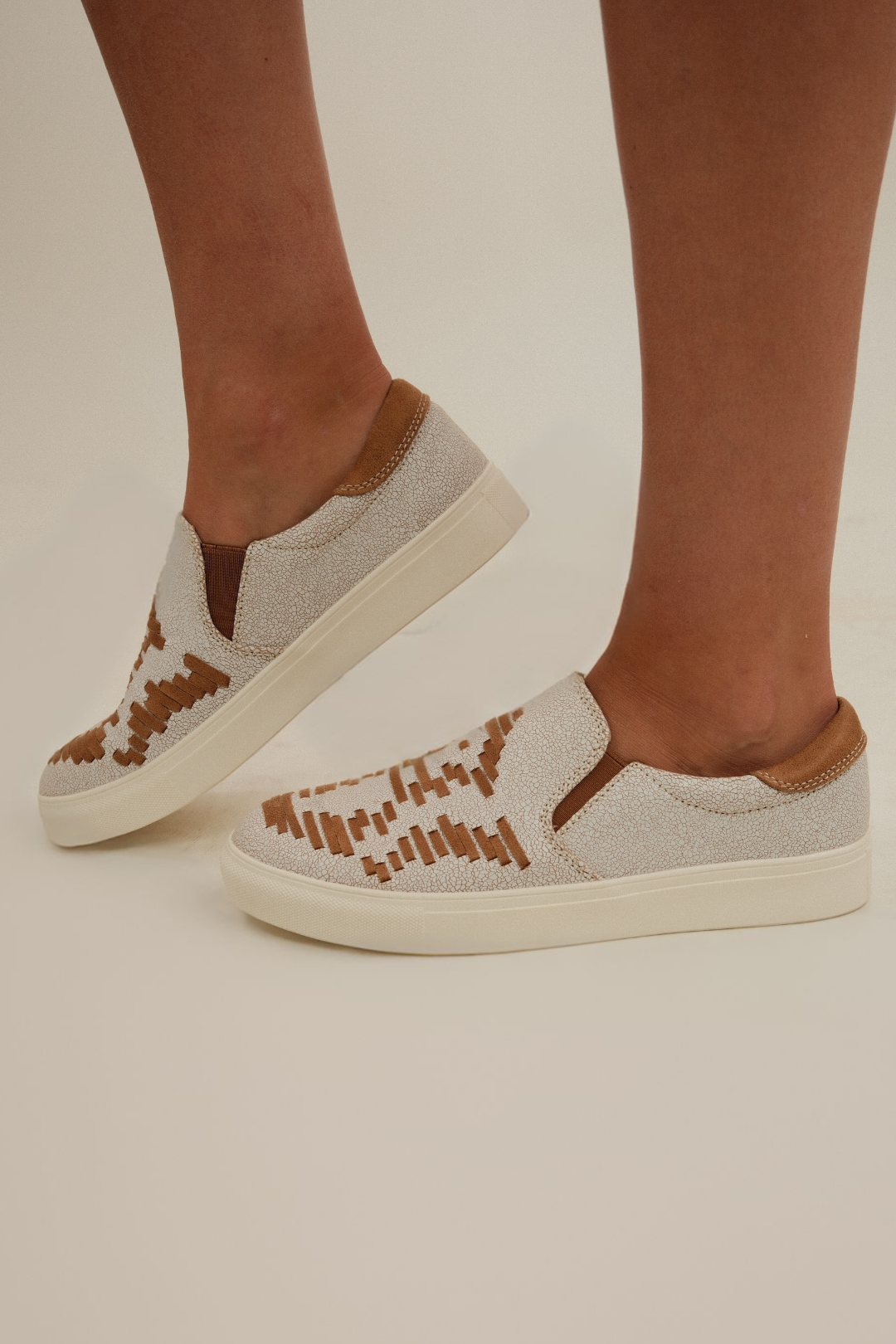 Tan & cream slip-on shoes with western embroidery detail, flat sole, and casual rustic styling.