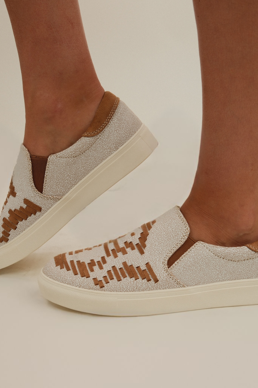 Side profile of Rustic Range Slip-Ons, tan and cream slip-on shoes with flat sole and stitched detail.