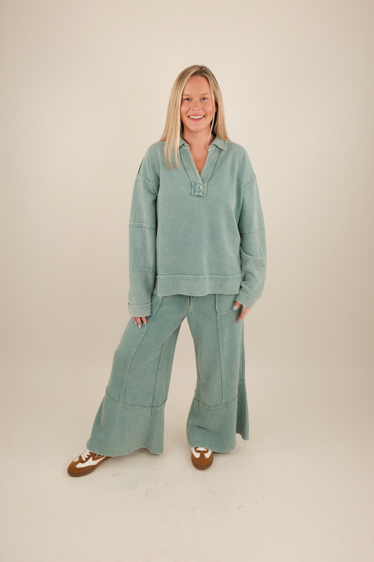 Woman wearing a teal tracksuit on a beige background
