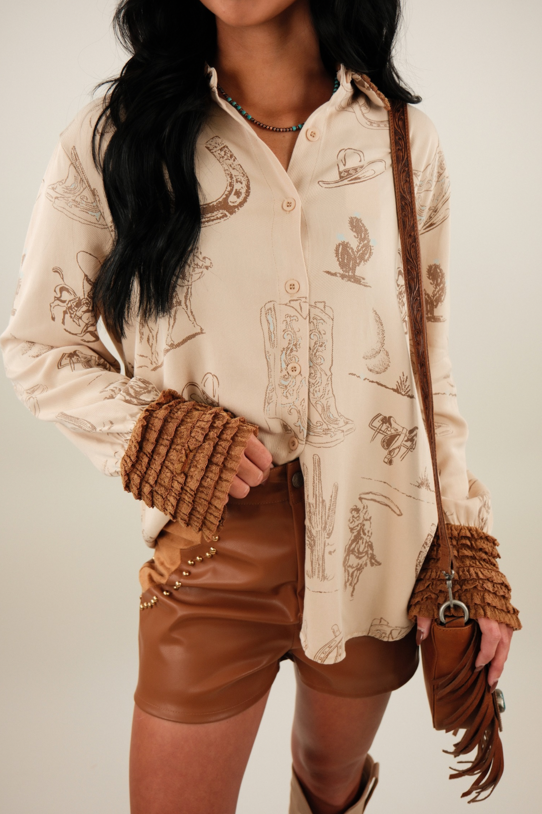 Close-up of Saddle Lace Button-Up highlighting brown lace ruffle trim at collar and cuffs, with boots, horseshoes and cacti motif print.
