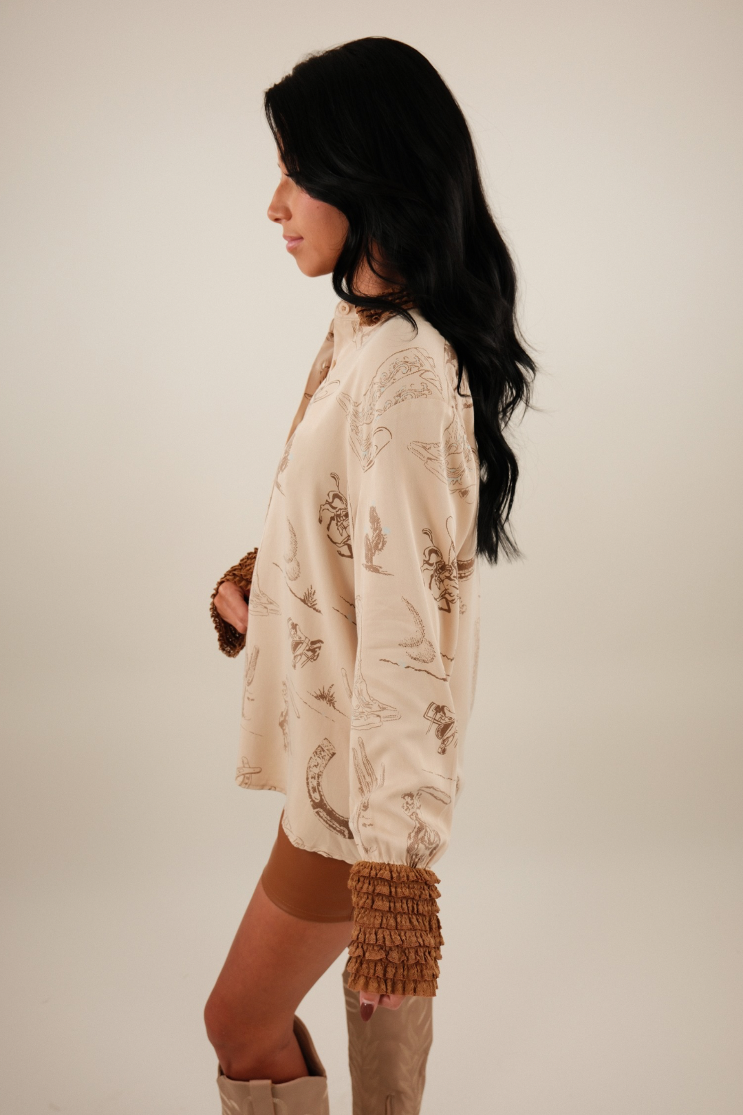 Side profile of Saddle Lace Button-Up showing beige western print fabric with boots, horseshoes, cacti and lace-trimmed sleeve cuff.