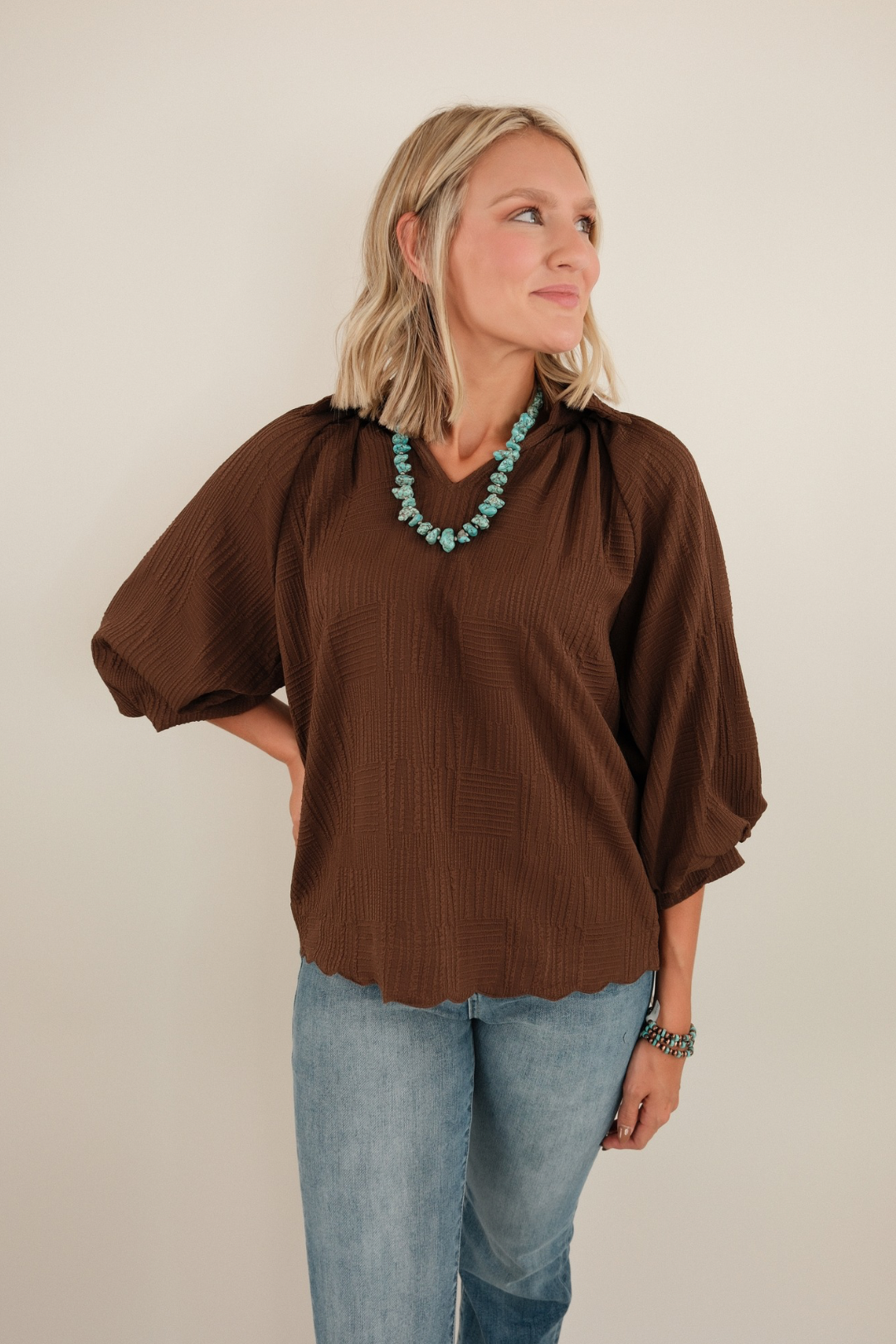 Textured chocolate-brown Saddle Mocha blouse with notched v-neck, structured collar, and long sleeves with elastic cuffs (western chic).