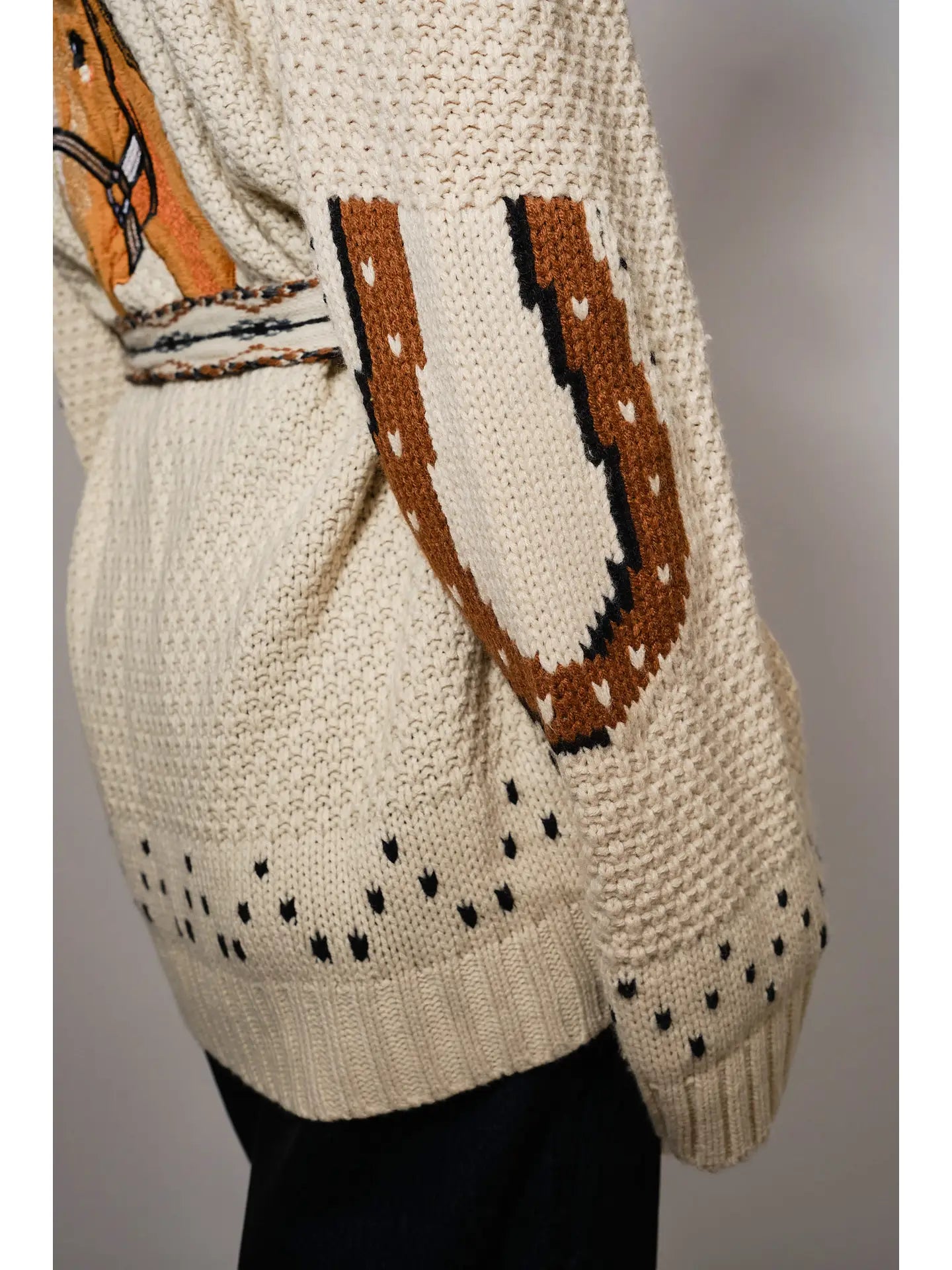 Knitted cardigan with horse shoe design on a plain background