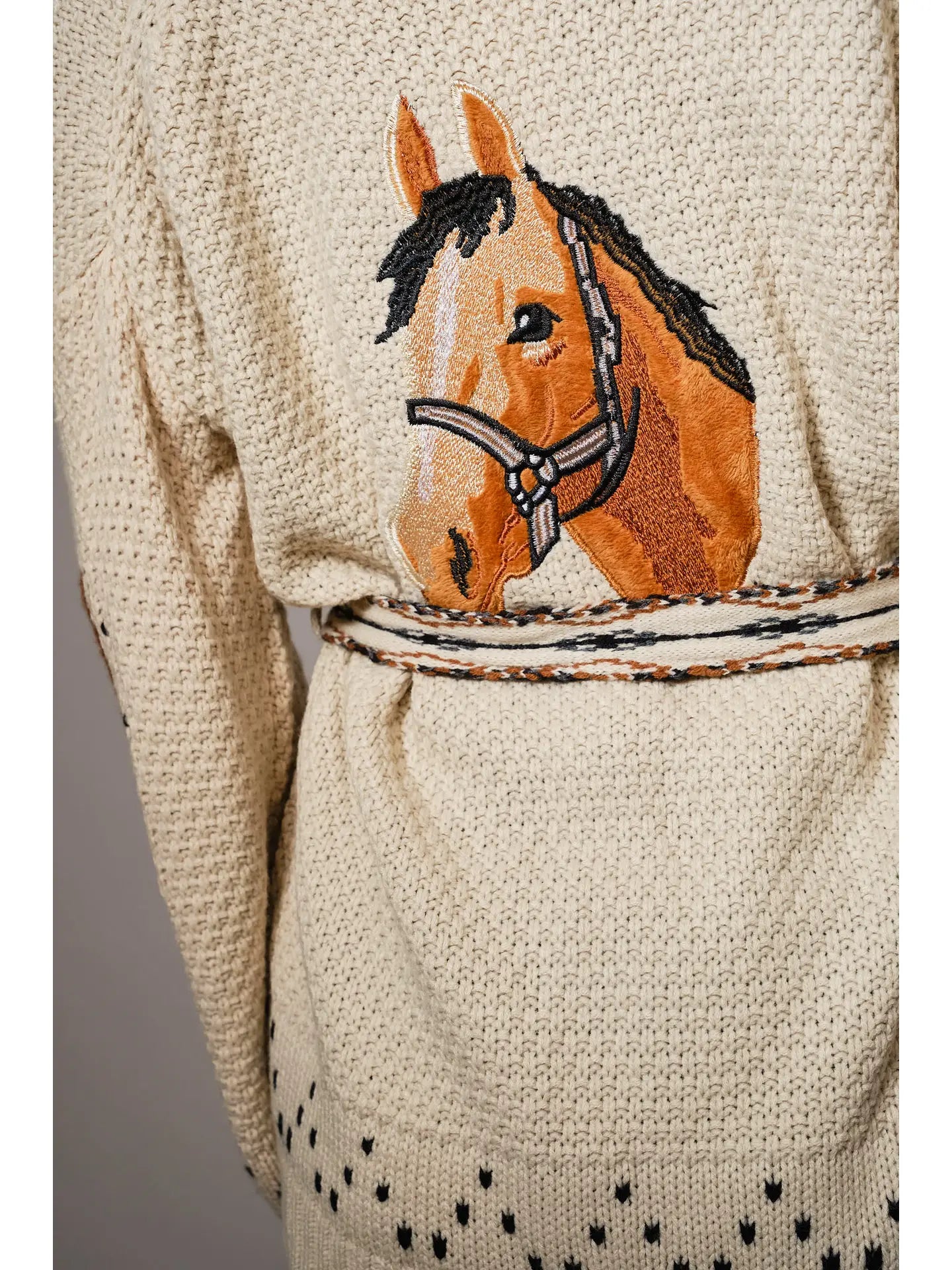 Beige cardigan with an embroidered horse design on a plain background