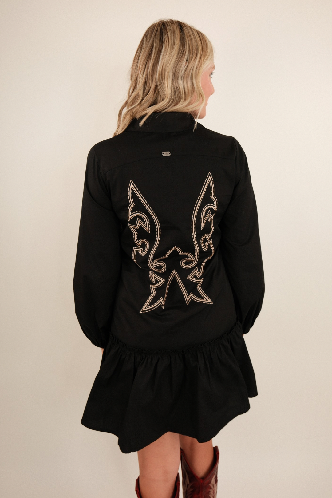 Back view of Saddle & Stitch Dress in black featuring boot stitch embroidery and flared ruffle hemline.