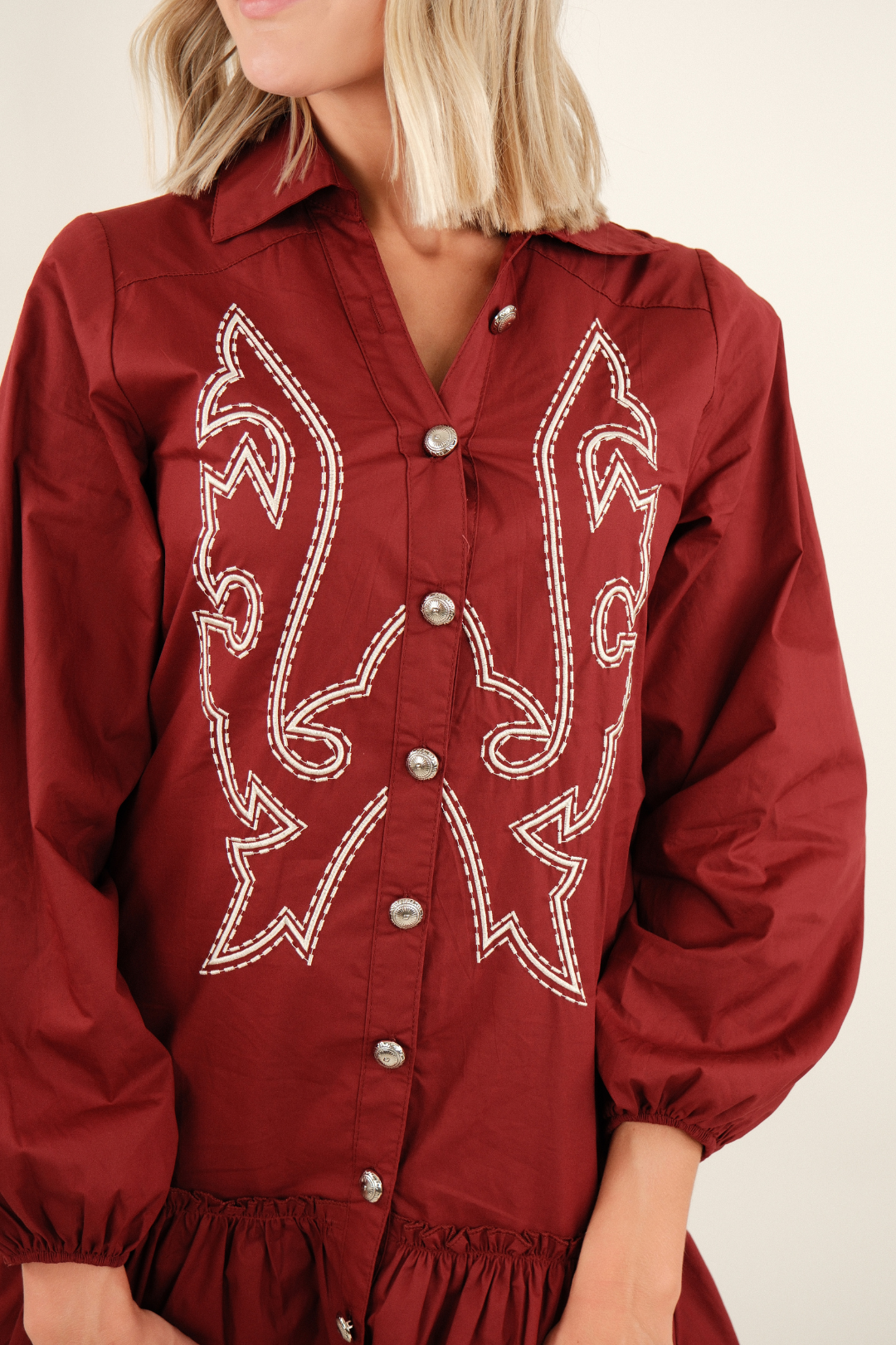 Close-up of Saddle & Stitch Dress in burgundy highlighting concho buttons, boot stitch embroidery and soft fabric detail.