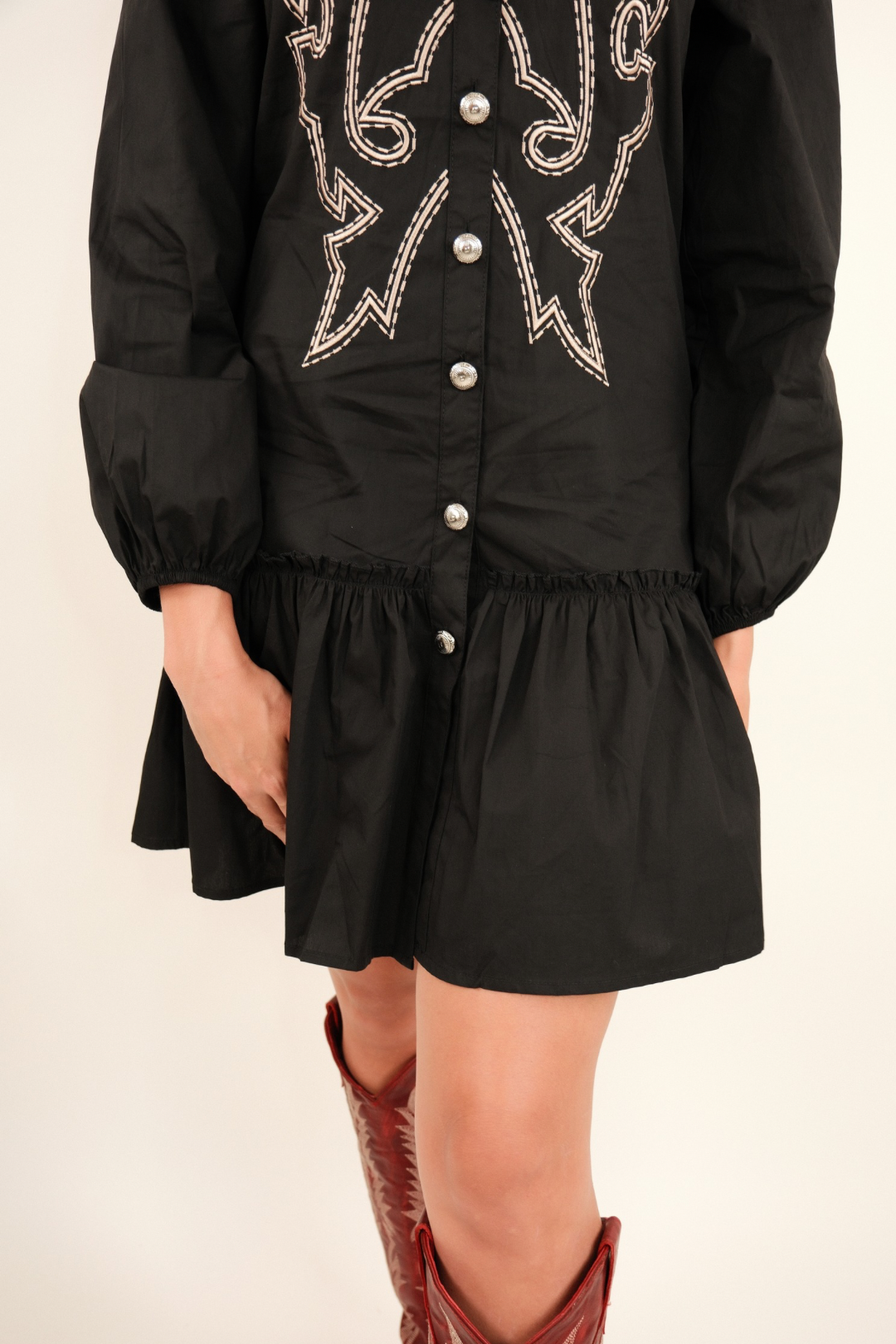 Close-up view of Saddle & Stitch Dress in black showing concho button detail, peplum ruffle hem and relaxed fit.