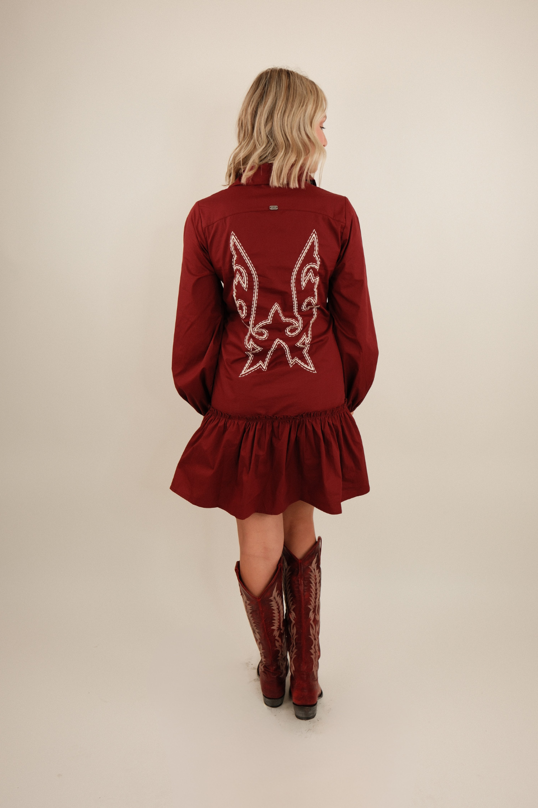 Back view of Saddle & Stitch Dress in burgundy featuring boot stitch embroidery and flared ruffle hemline.