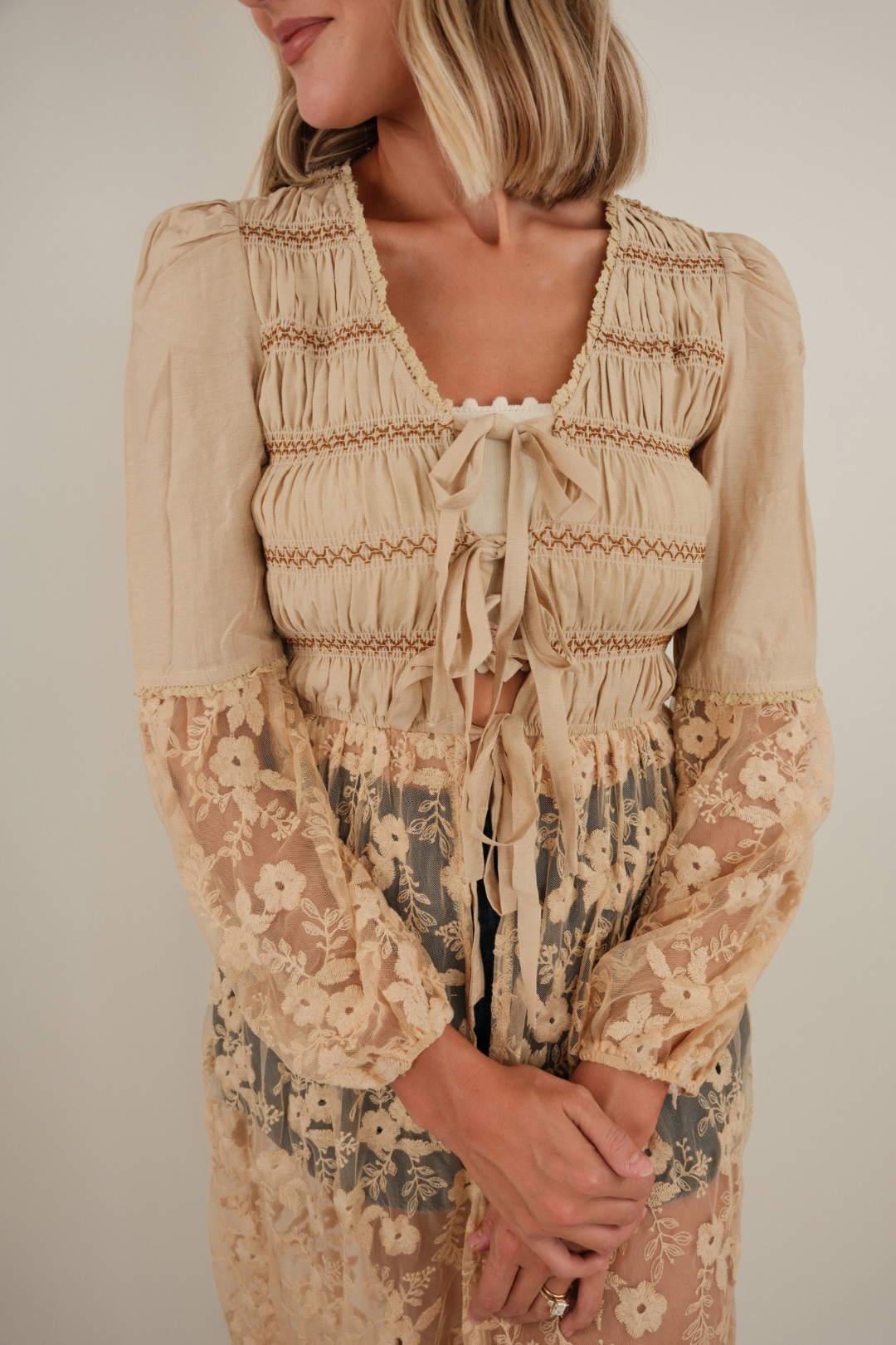 Close-up of Saddlewood Lace Duster highlighting lace ruffle trim, tie-front detail and western-inspired tan cotton fabric.
