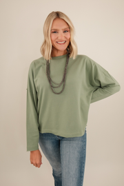 Women’s Sage Haven High Low Terry Top in sage green French terry with raw-edge hemline, high-low silhouette, oversized fit — western casual layering piece.