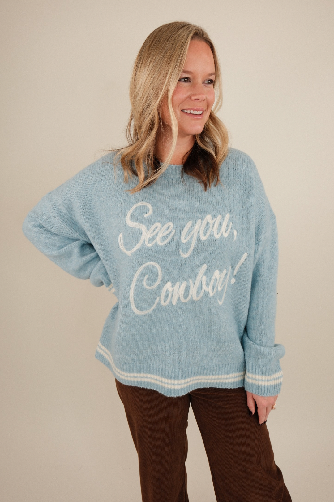 Front view of See You Cowboy Embroidered Sweater, light blue wool-blend knit with ivory trim and embroidered ‘See You Cowboy’ script on chest.