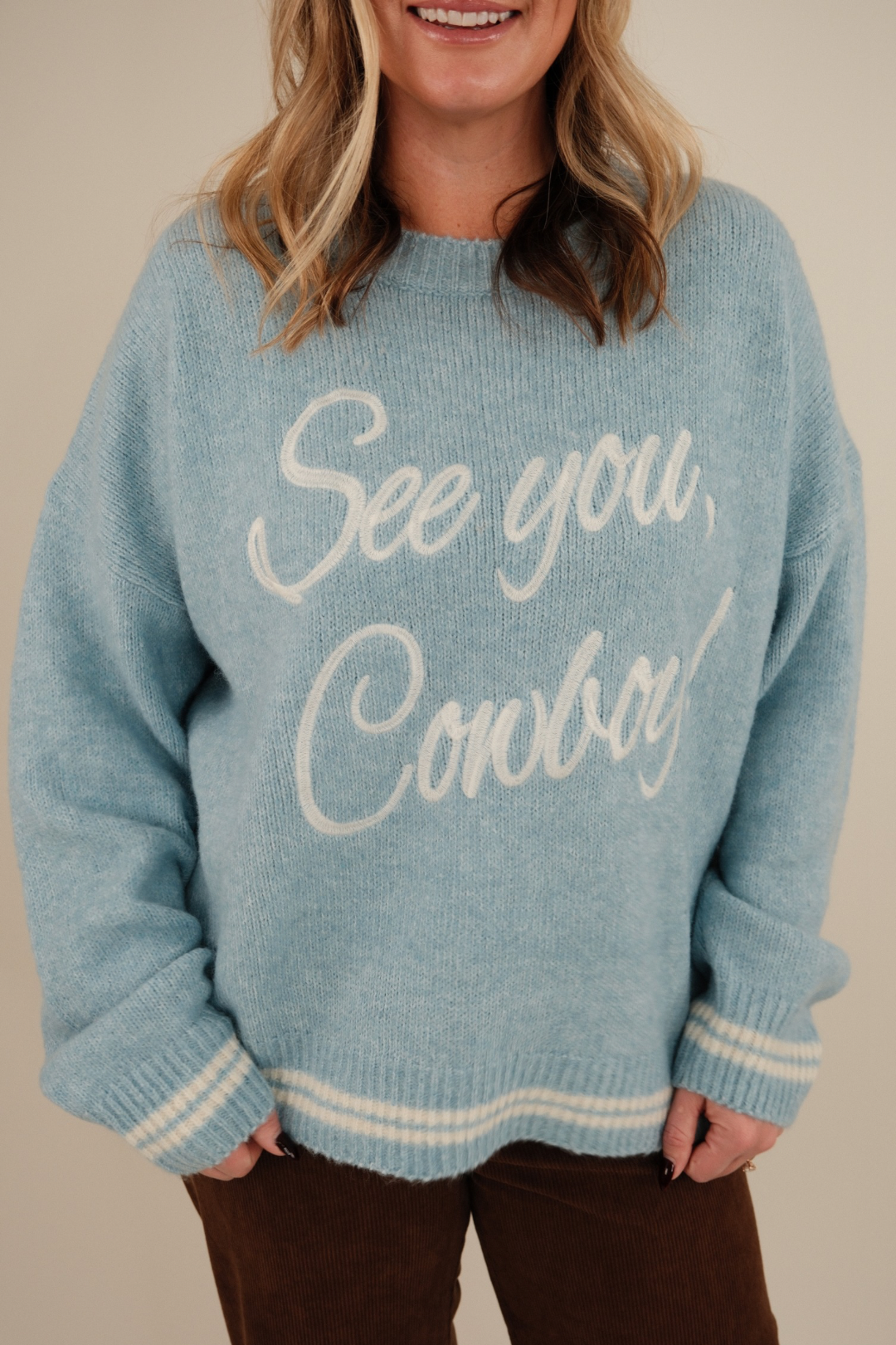 Close-up of See You Cowboy Embroidered Sweater highlighting bold chest embroidery, ivory trim, and soft textured light blue knit.