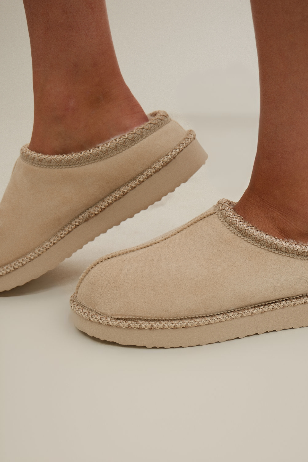 Side profile of Sierra Luxe Slip-Ons, cream faux leather with cozy fur trim and slip-on design.