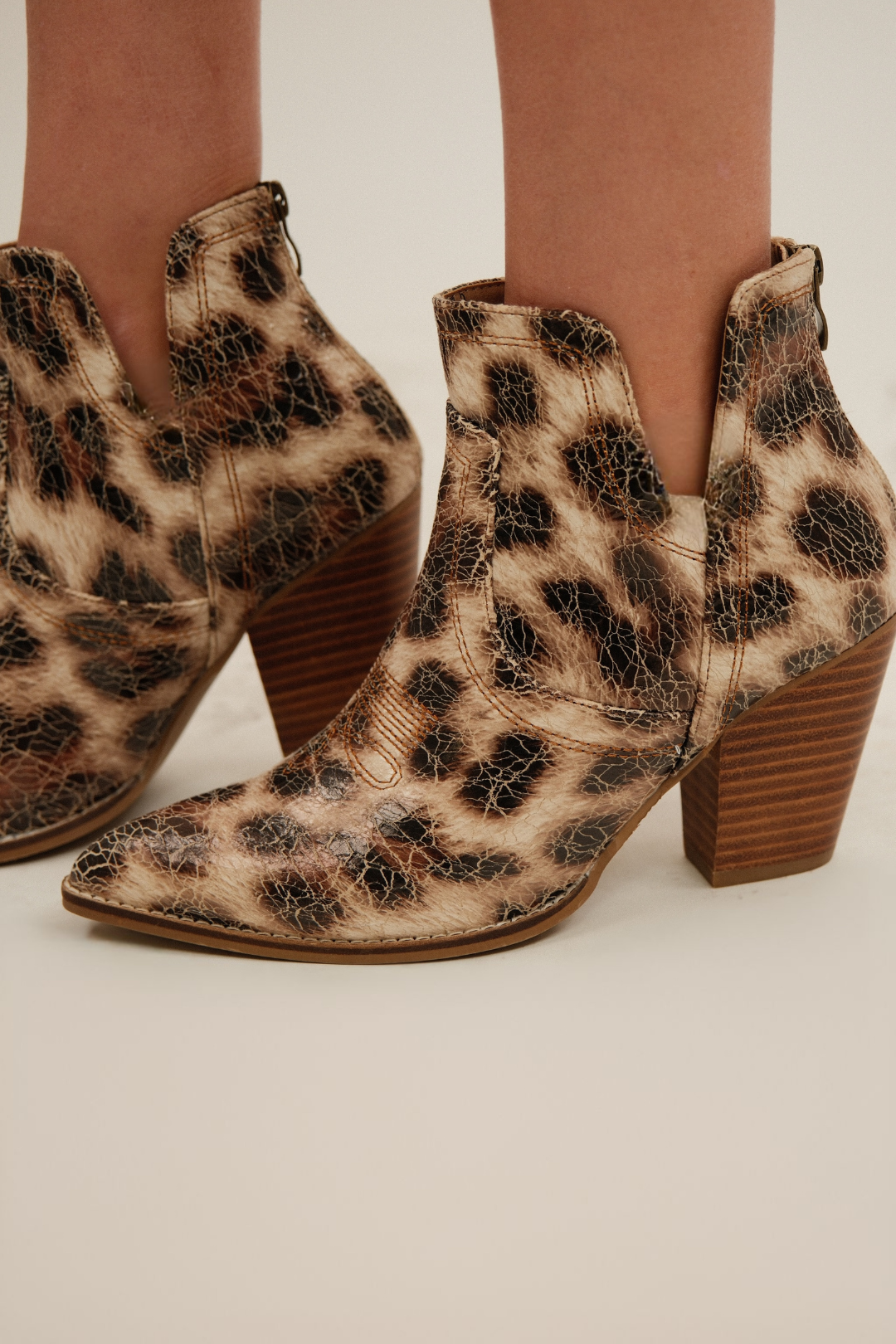 Side profile of cheetah booties, cream crackle ankle boots with western stitching and stacked heel.