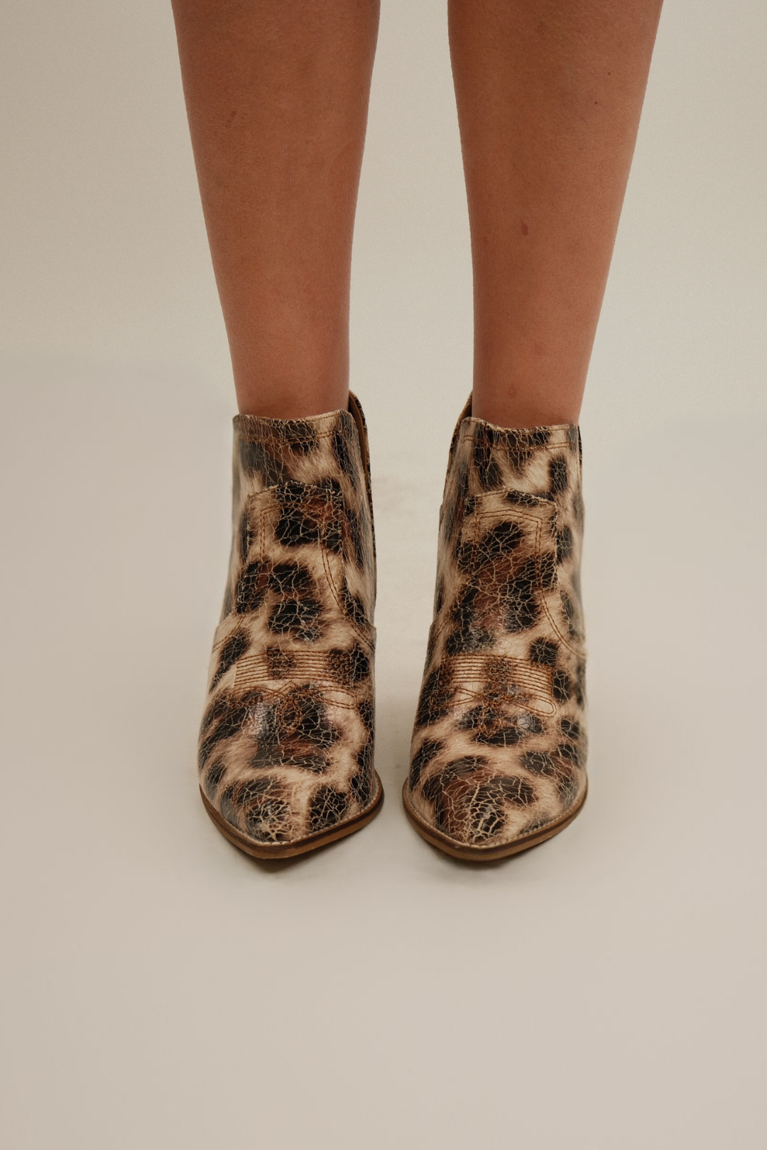 Front view of women’s cheetah booties in cream crackle finish with pointed toe and western stitching.