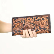 Hand holding a brown leather wallet with floral patterns on a white background