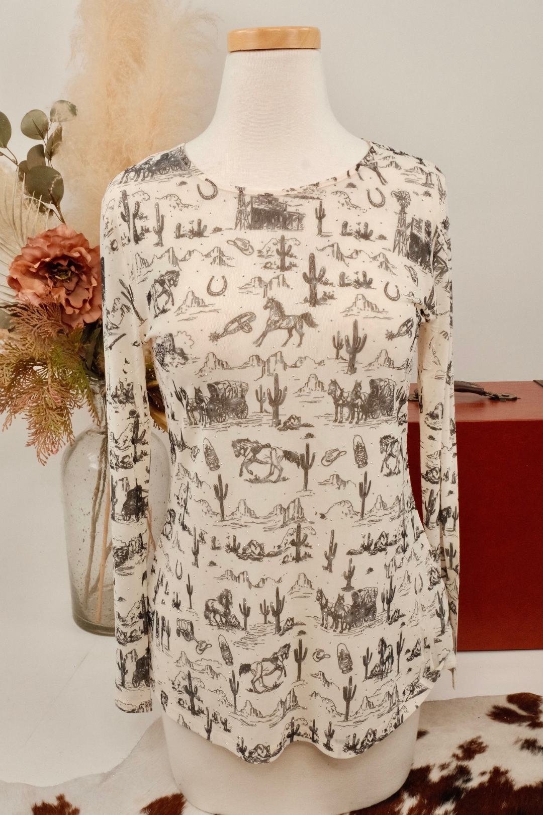 Mannequin wearing a mesh shirt with a desert-themed pattern against a neutral background