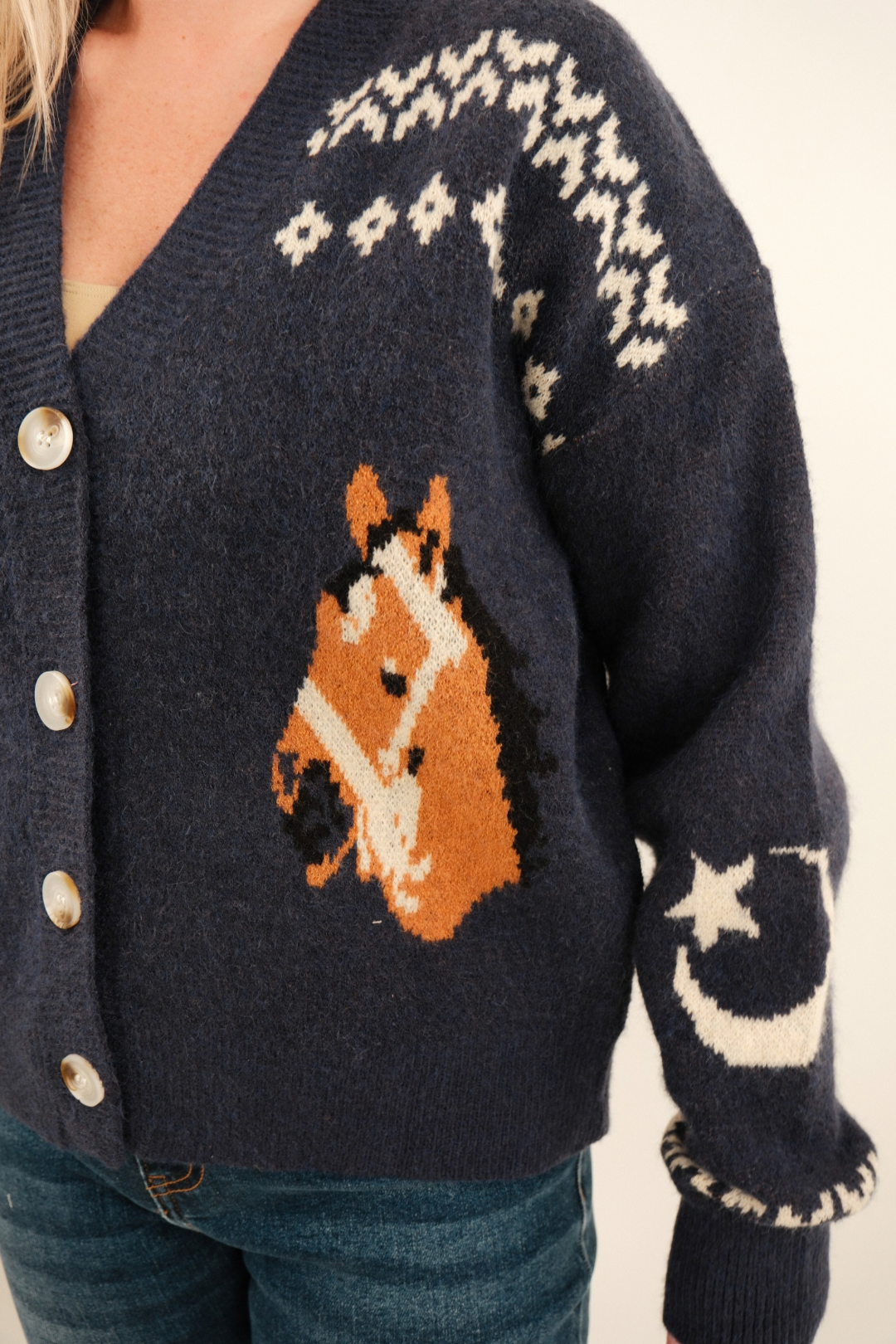 Close-up of navy women’s Starlight Mustang Cardigan highlighting cream knit stitching, western horse motif and button detail.
